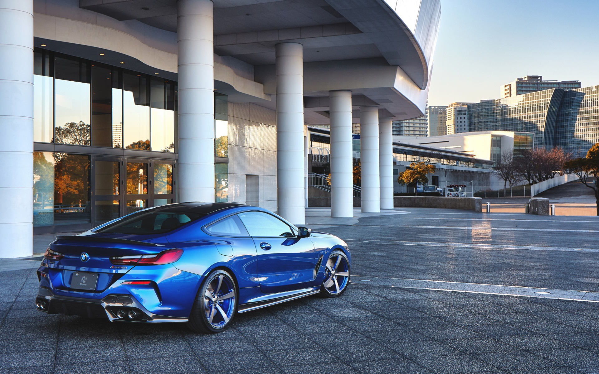 Синий автомобиль BMW M850i XDrive Coupe 2020 года у здания вид сзади