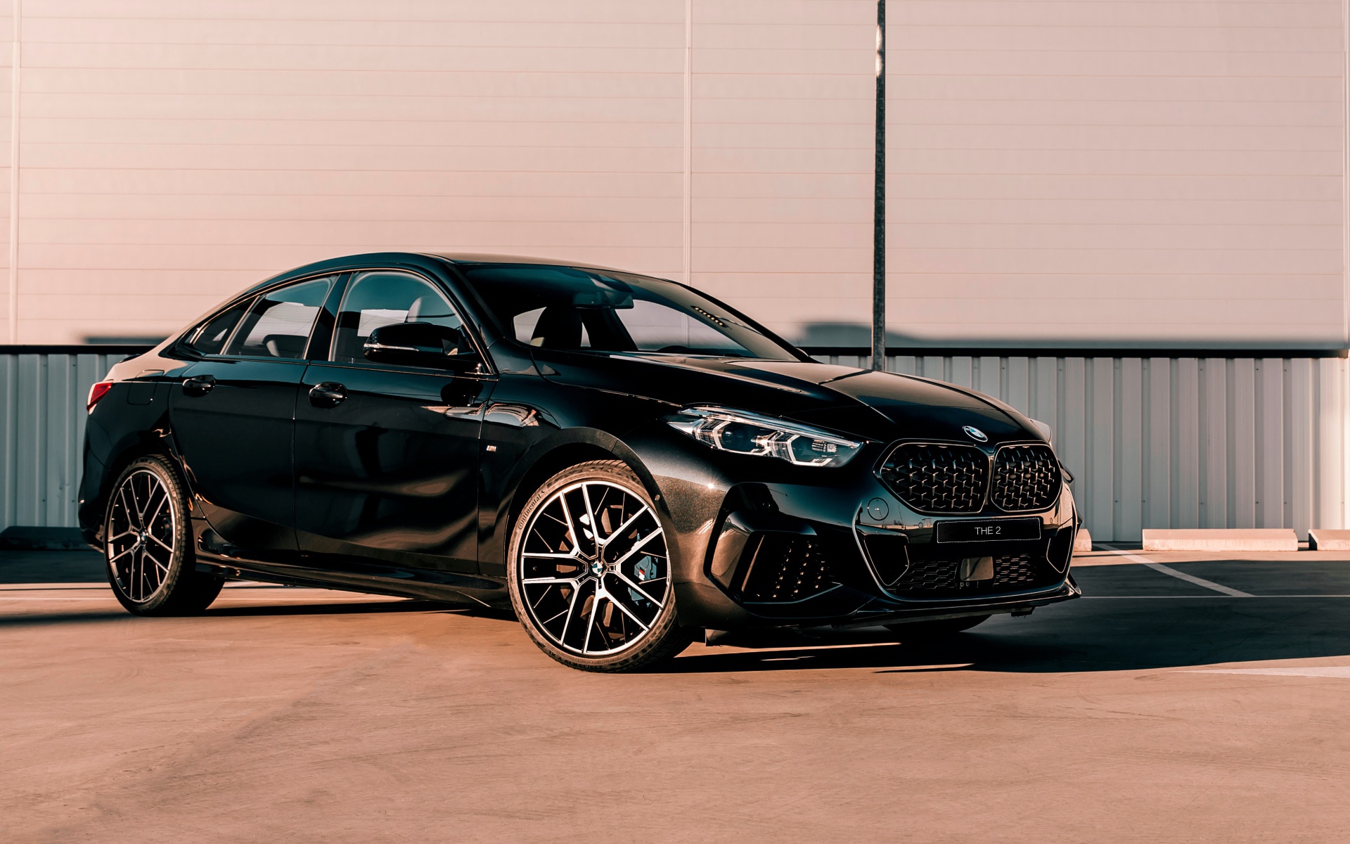 Черный автомобиль BMW M235i XDrive Gran, 2020 года у белого здания 