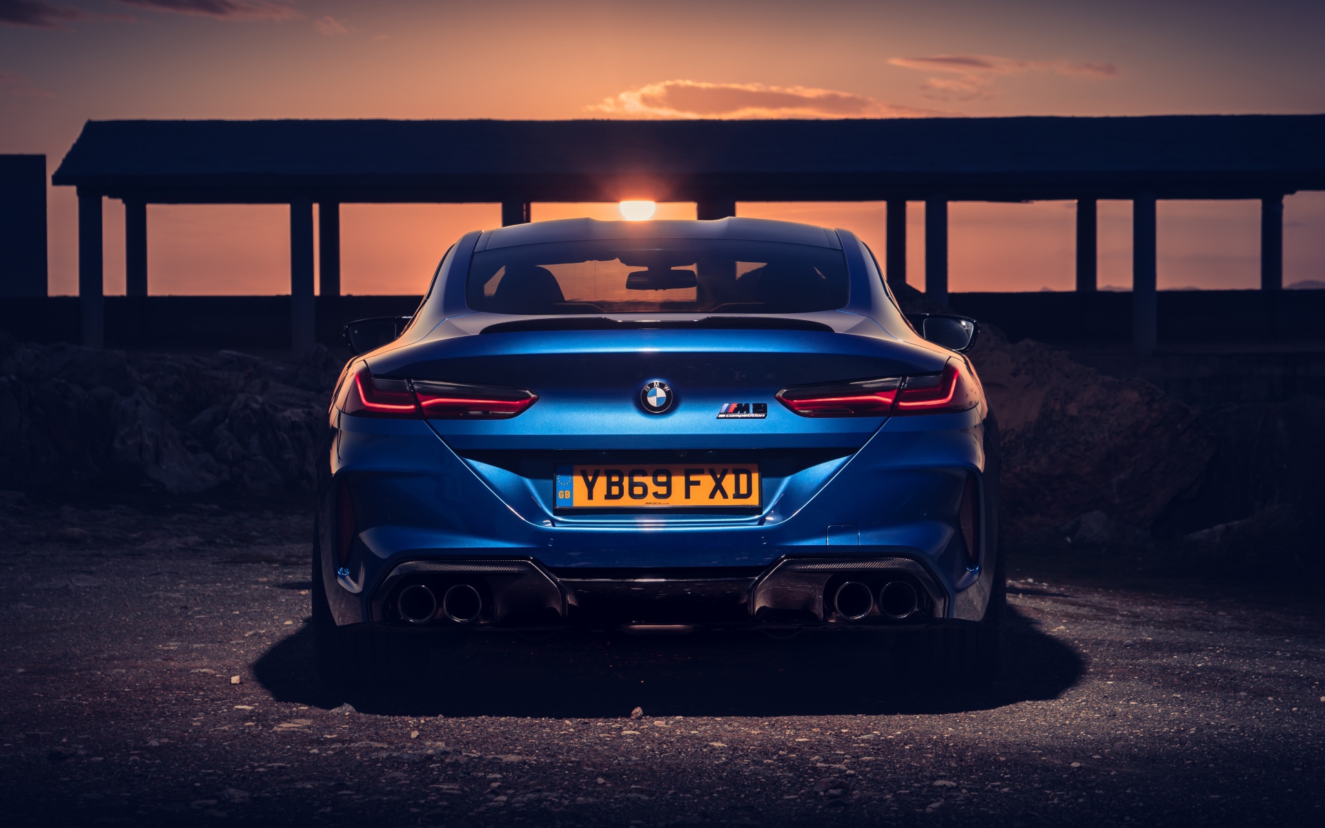 Синий автомобиль BMW M8, 2019 года на фоне заката 