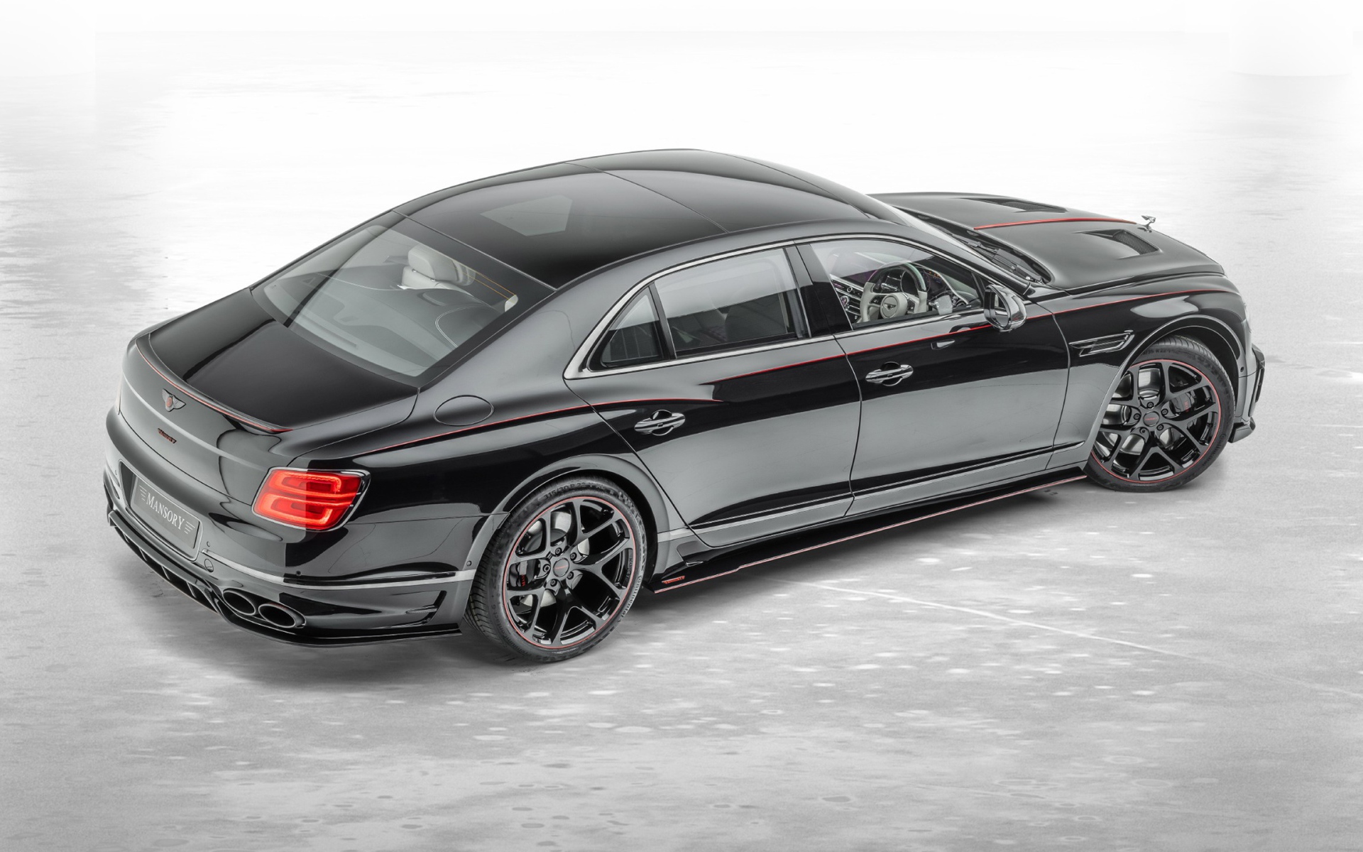 Черный автомобиль Mansory Bentley Flying Spur 2020 года на сером фоне