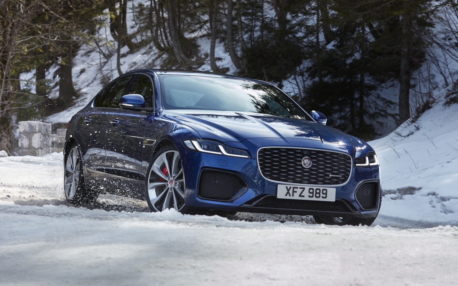 Синий Jaguar XF P300 AWD R-Dynamic 2020 года в заснеженном лесу 