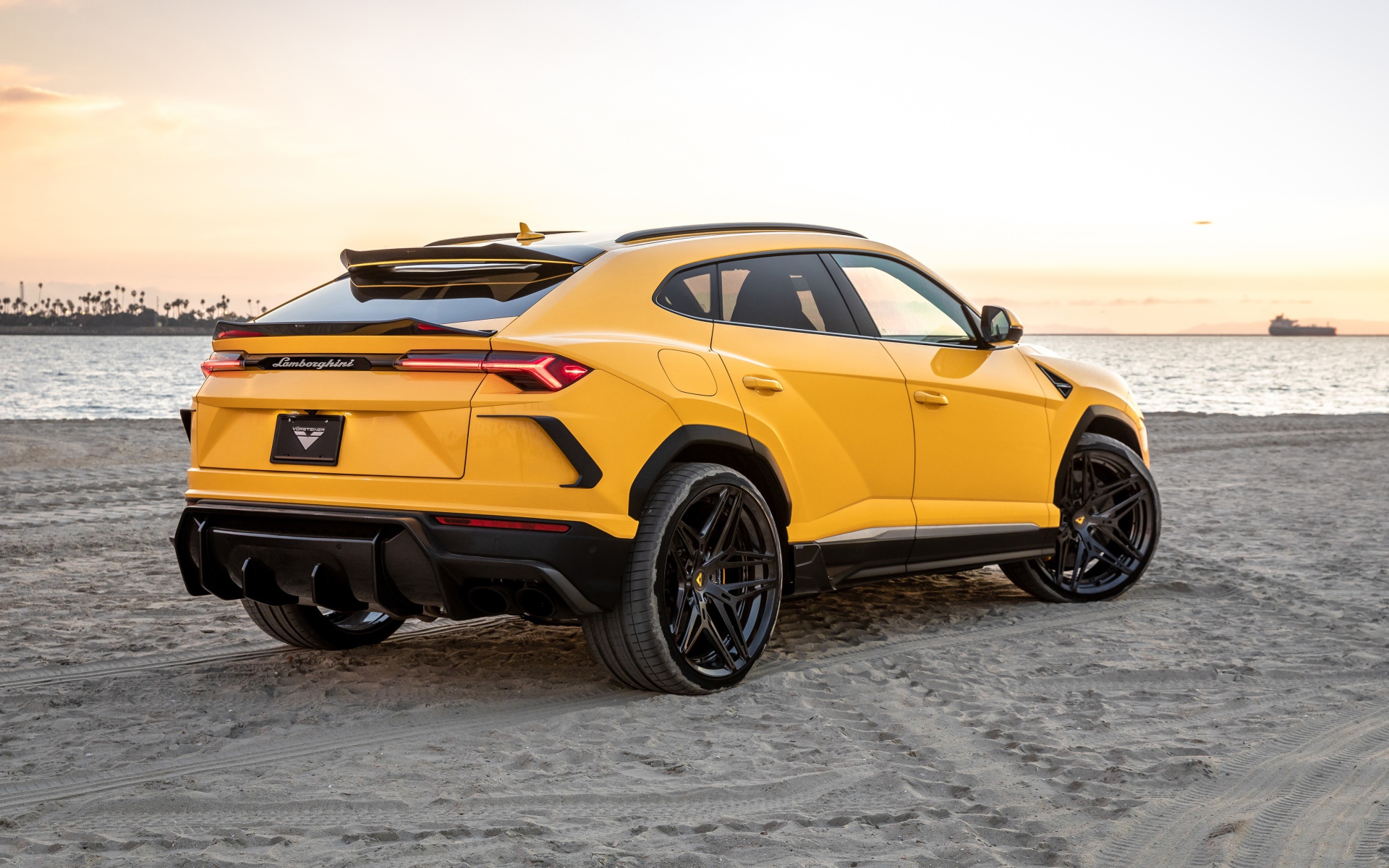 Желтый автомобиль  Lamborghini Urus на песке у моря