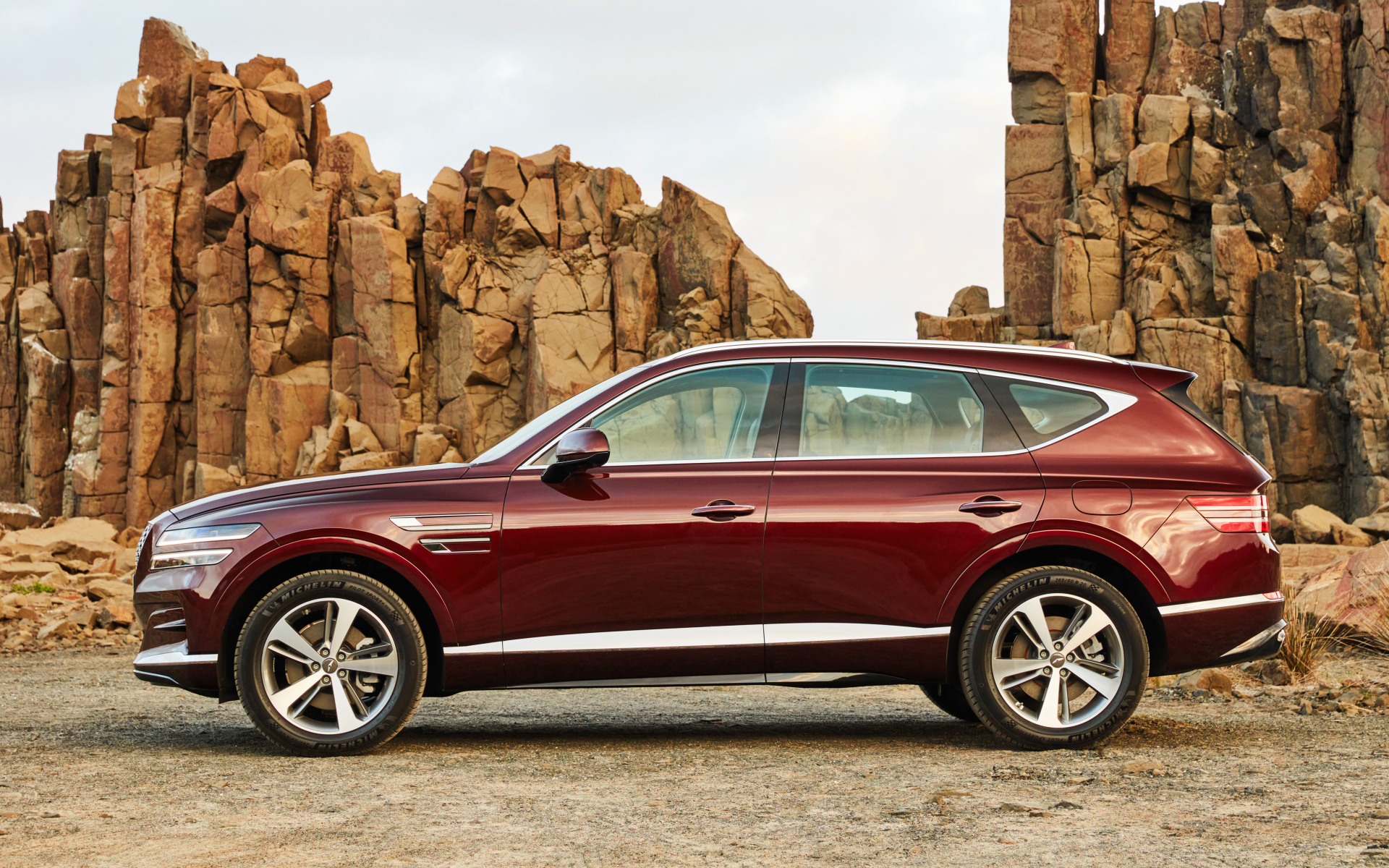 Бордовый автомобиль Genesis GV80 2.5T 2020 года на фоне гор