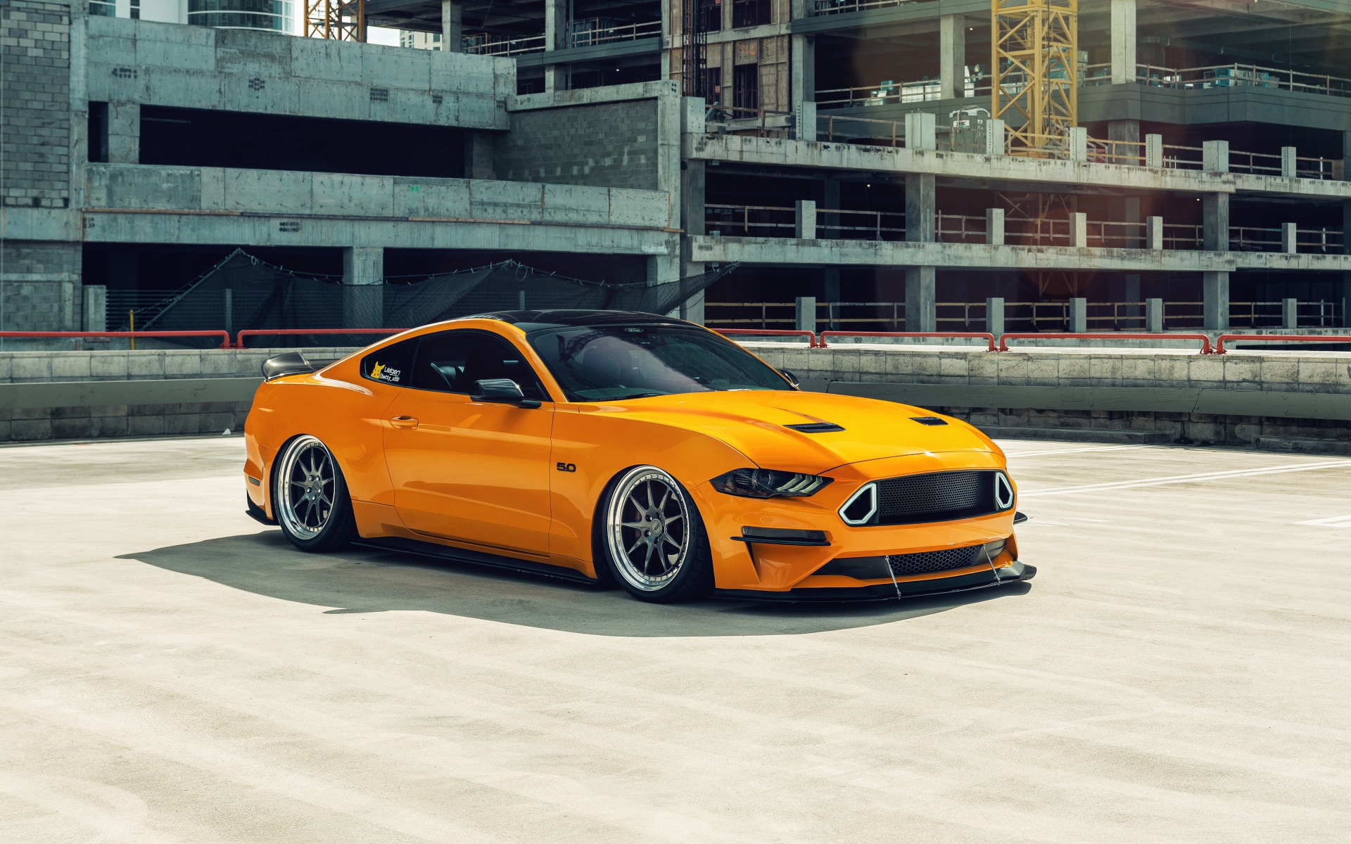 Оранжевый автомобиль Mustang у заброшенного здания 