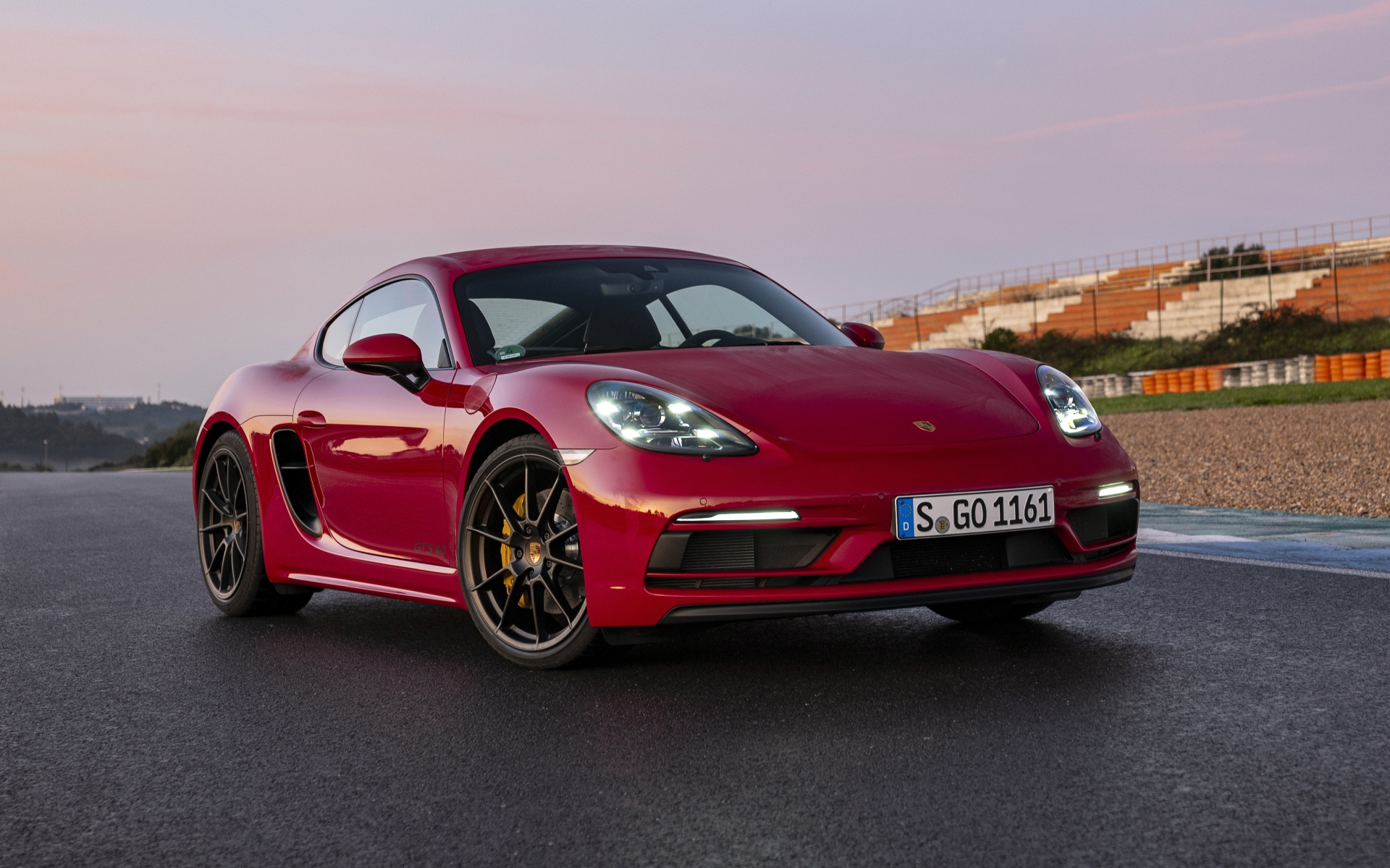 Красный автомобиль Porsche 718 Cayman GTS 4,  2020  года на стадионе