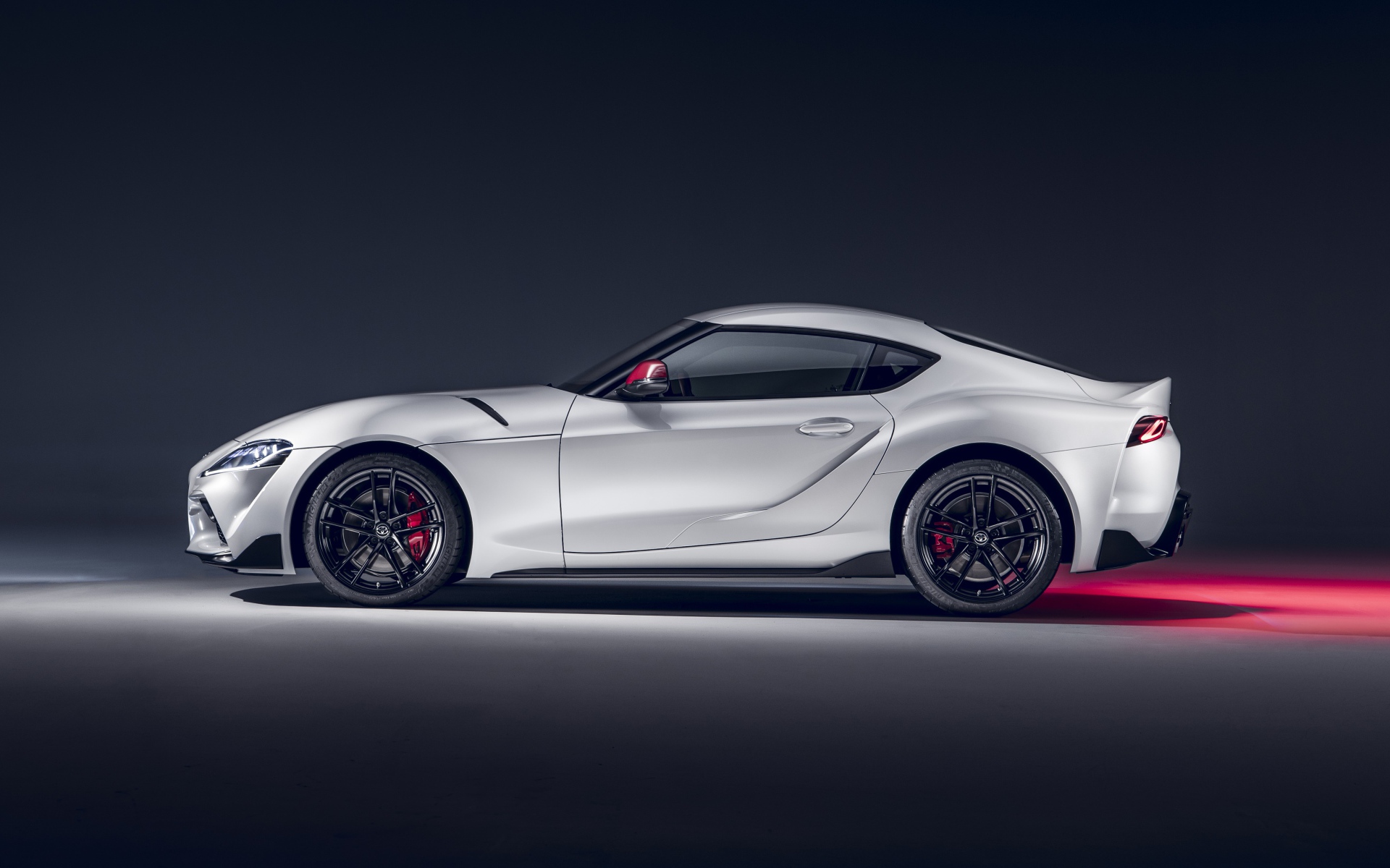 Серый автомобиль Toyota GR Supra 2L 2020 года вид сбоку на сером фоне