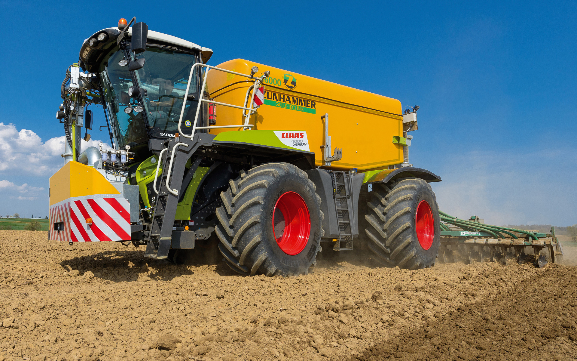 Большой комбайн пашет поле под голубым небом