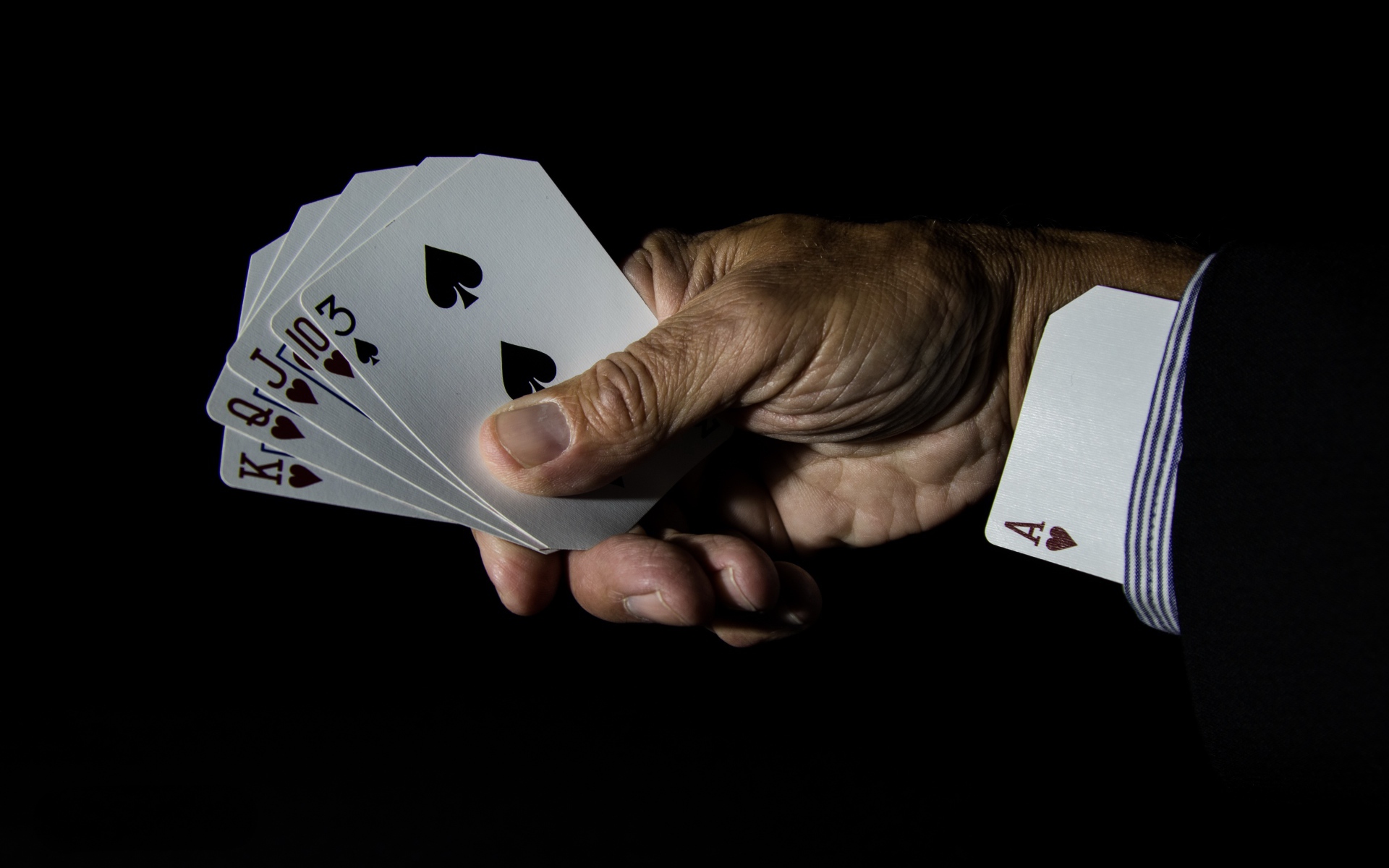 Туз в рукаве у шулера на черном фоне 