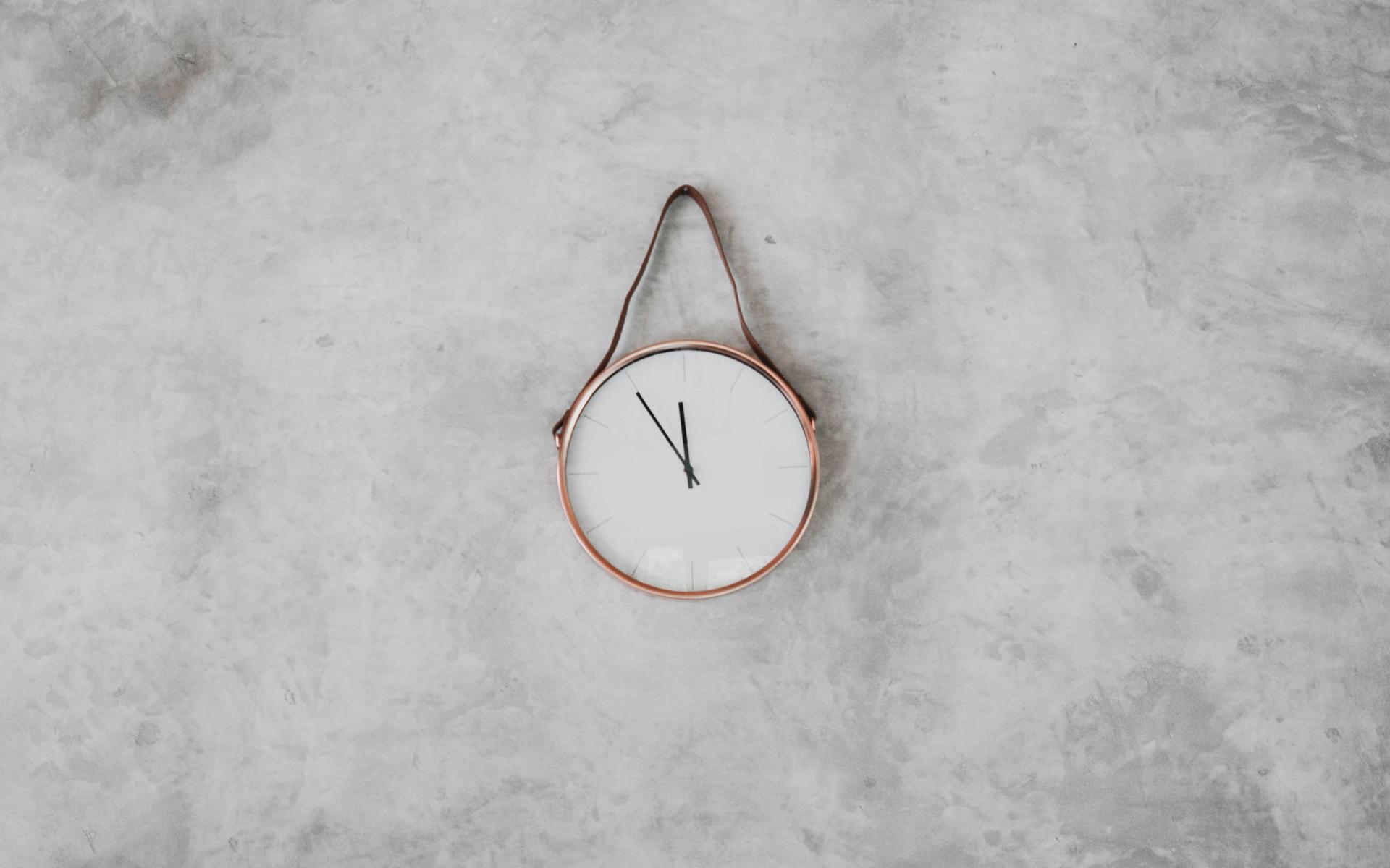 Часы с черными стрелками висят на серой стене 