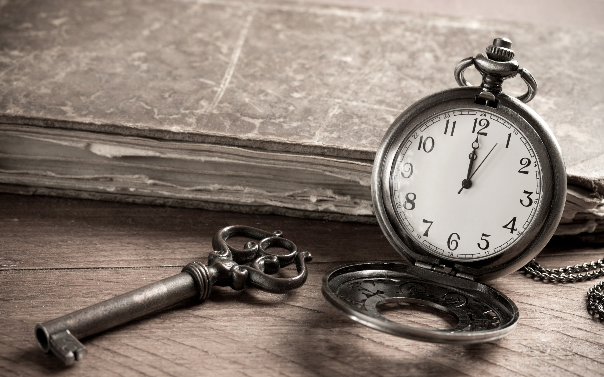 Карманные часы на столе с ключом и старой книгой 