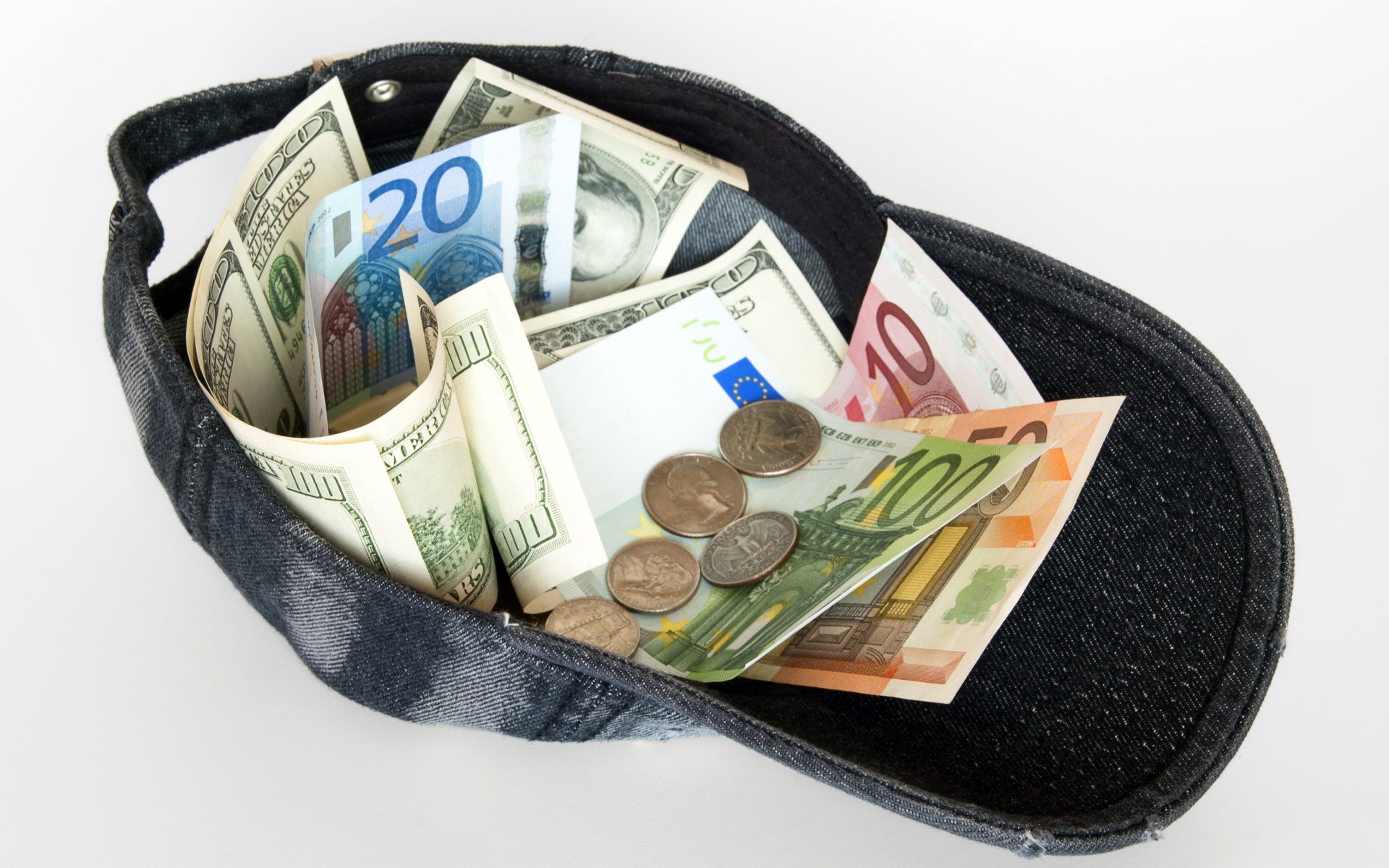 Бейсболка с купюрами и монетами на белом фоне