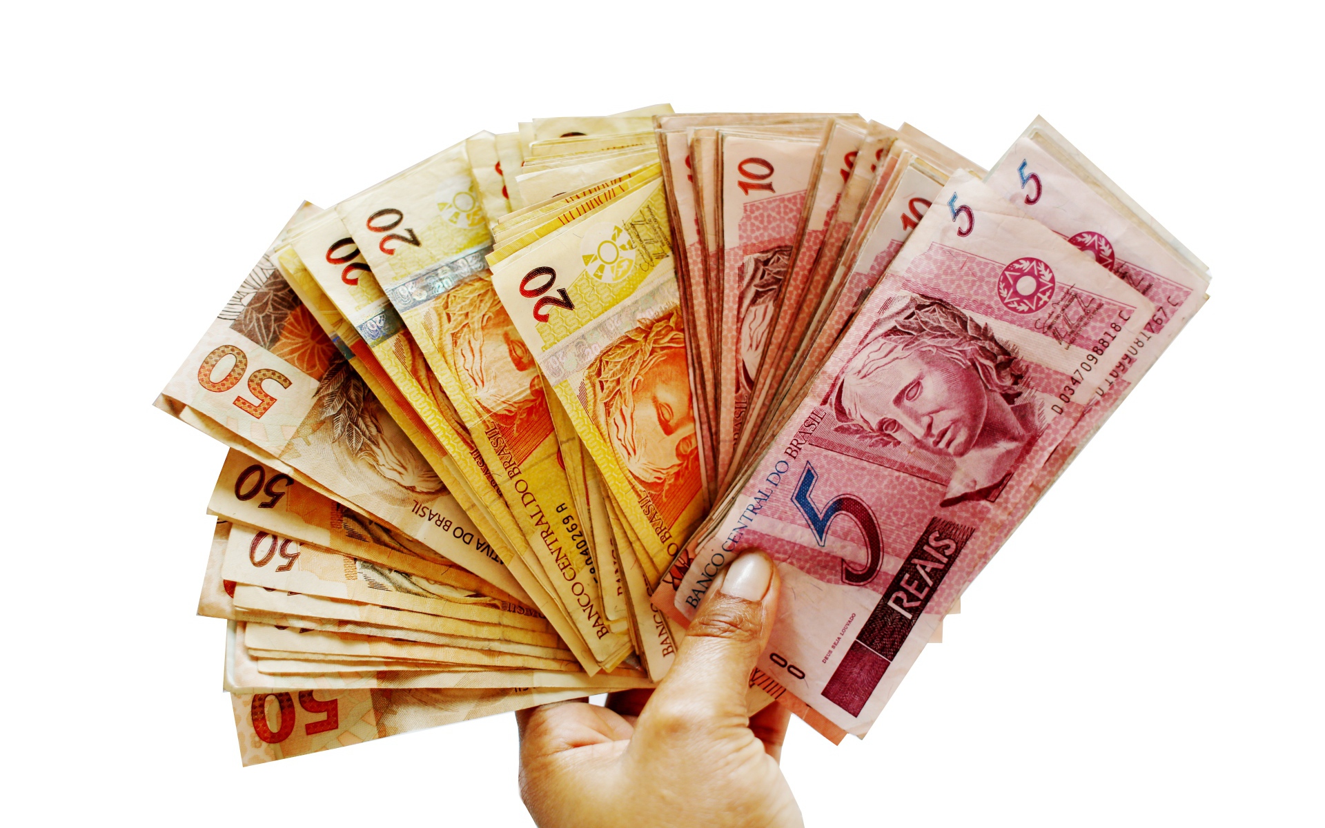 Много купюр бразильского реала в руке на белом фоне 