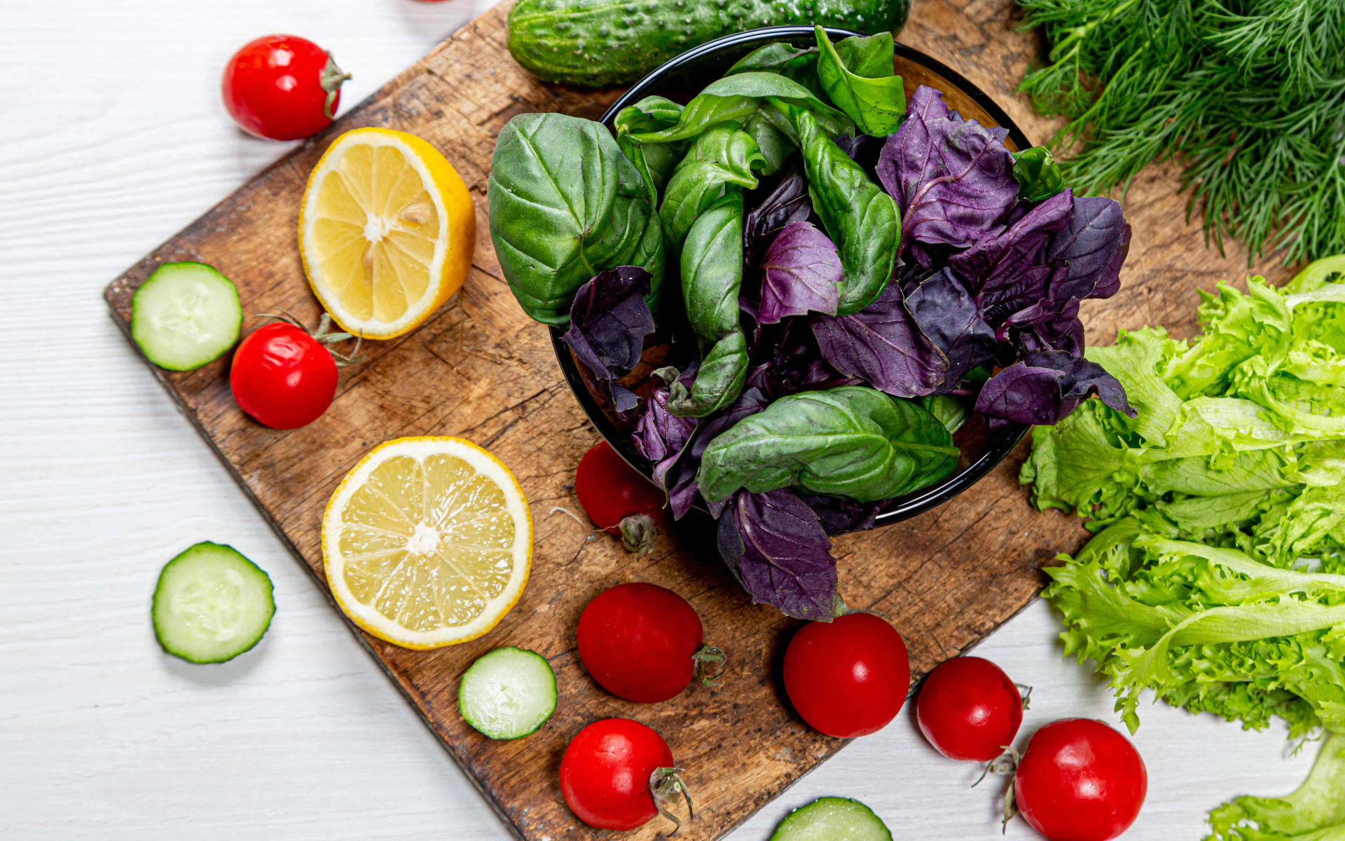 Базилик на столе с зеленью, помидорами и лимоном