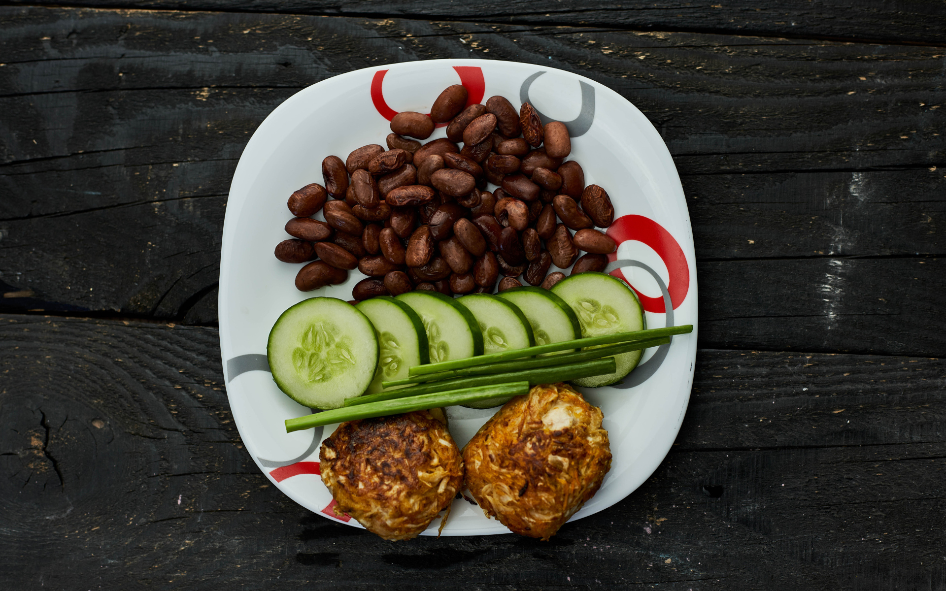 Фасоль на тарелке с оладьями и огурцами 