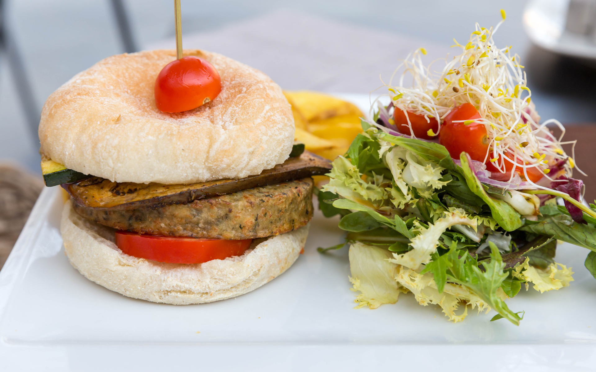 Большой гамбургер с салатом на столе 