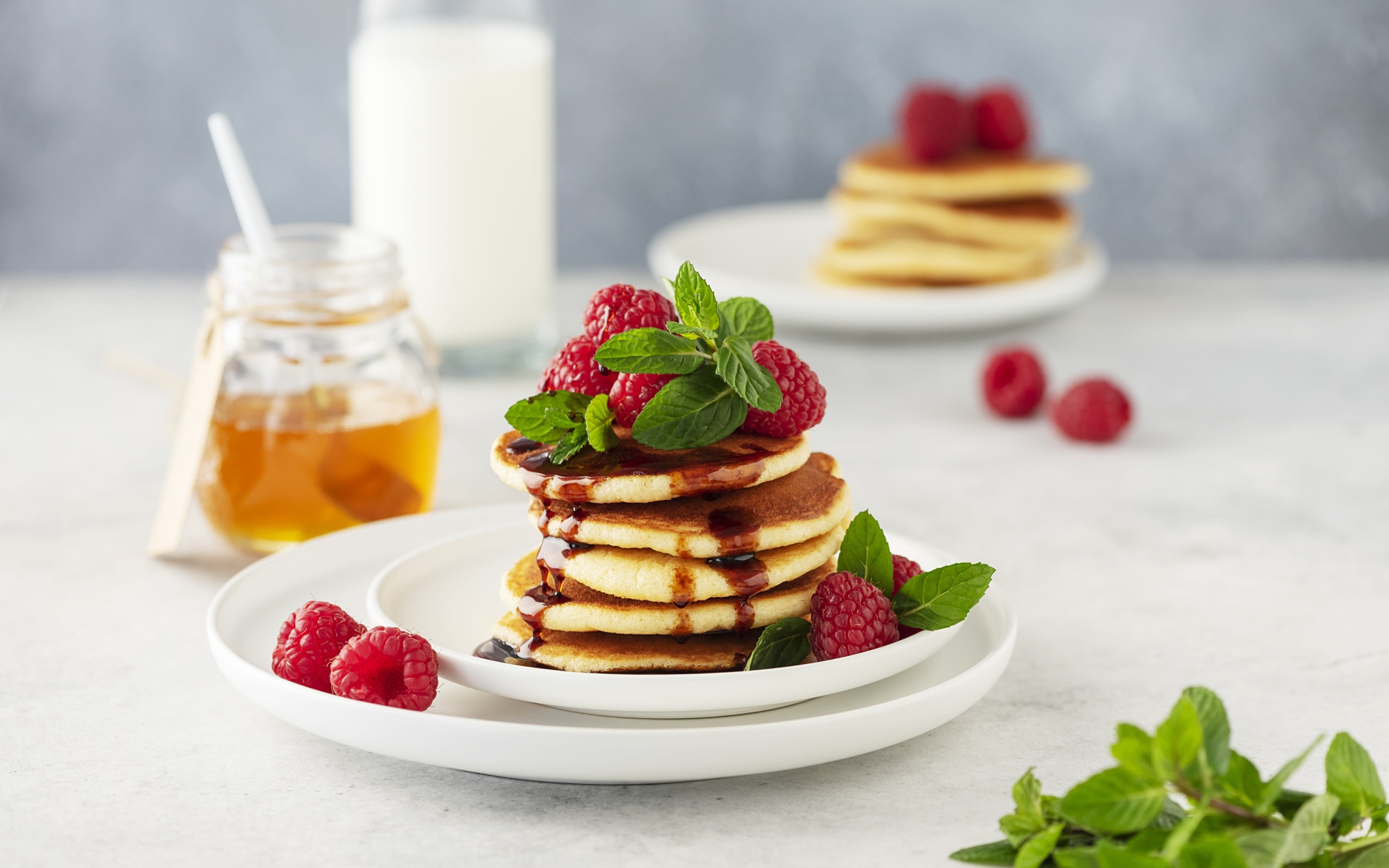Румяные оладьи на тарелке с малиной и мятой 