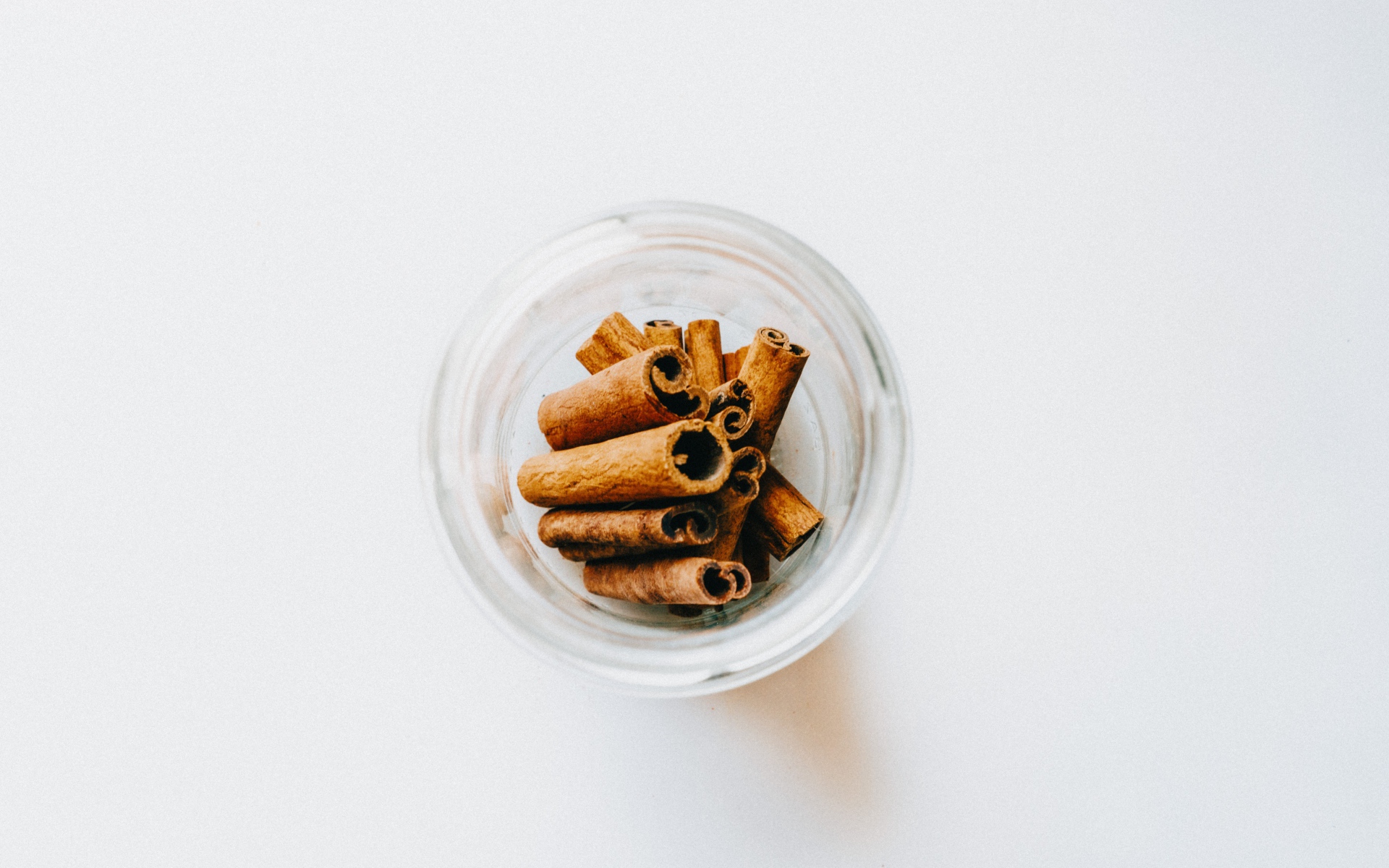 Cinnamon in a glass jar on a white background
