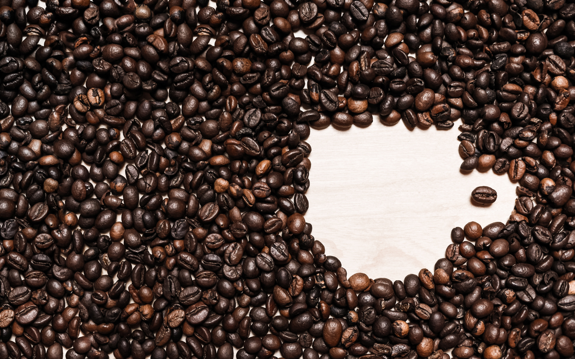 Рисунок чашки из кофейных зерен на столе