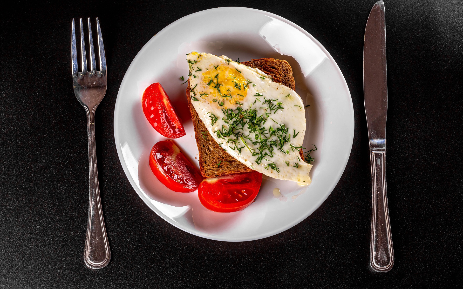 Бутерброд с яичницей на тарелке с помидорами