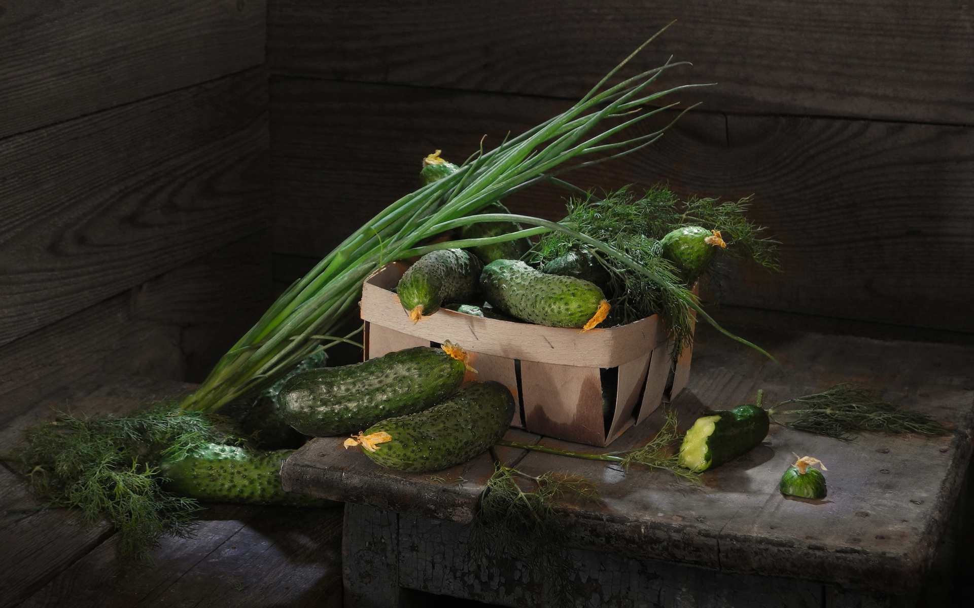 Свежие огурцы на столе  с зеленым луком и укропом