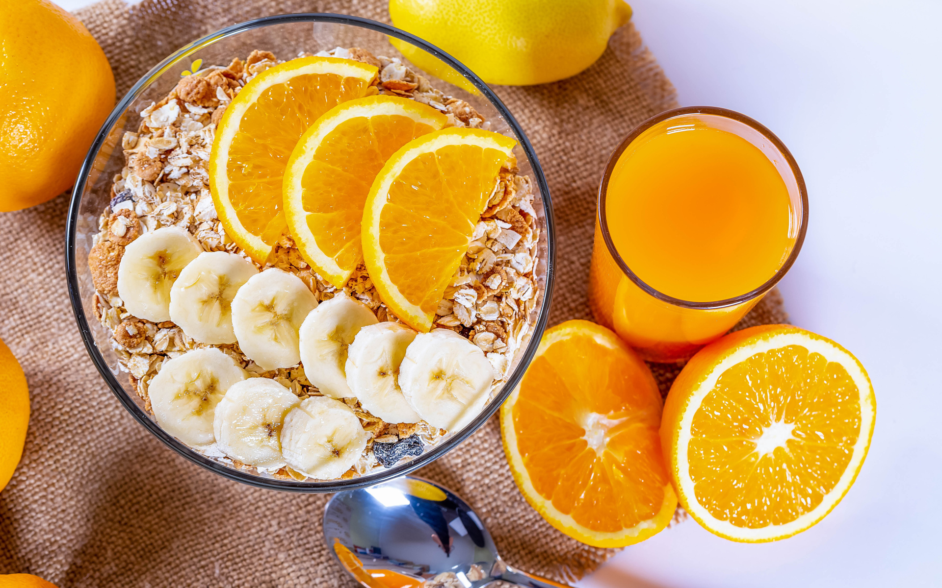 Овсяные хлопья в тарелке с кусочками банана и апельсина на столе с соком