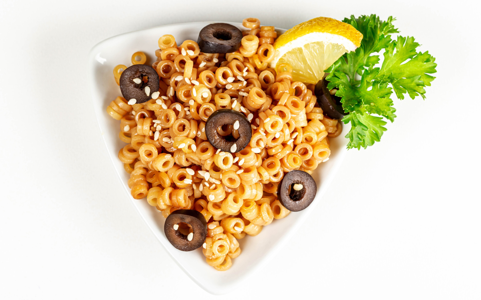 Макароны на тарелке с оливками и лимоном