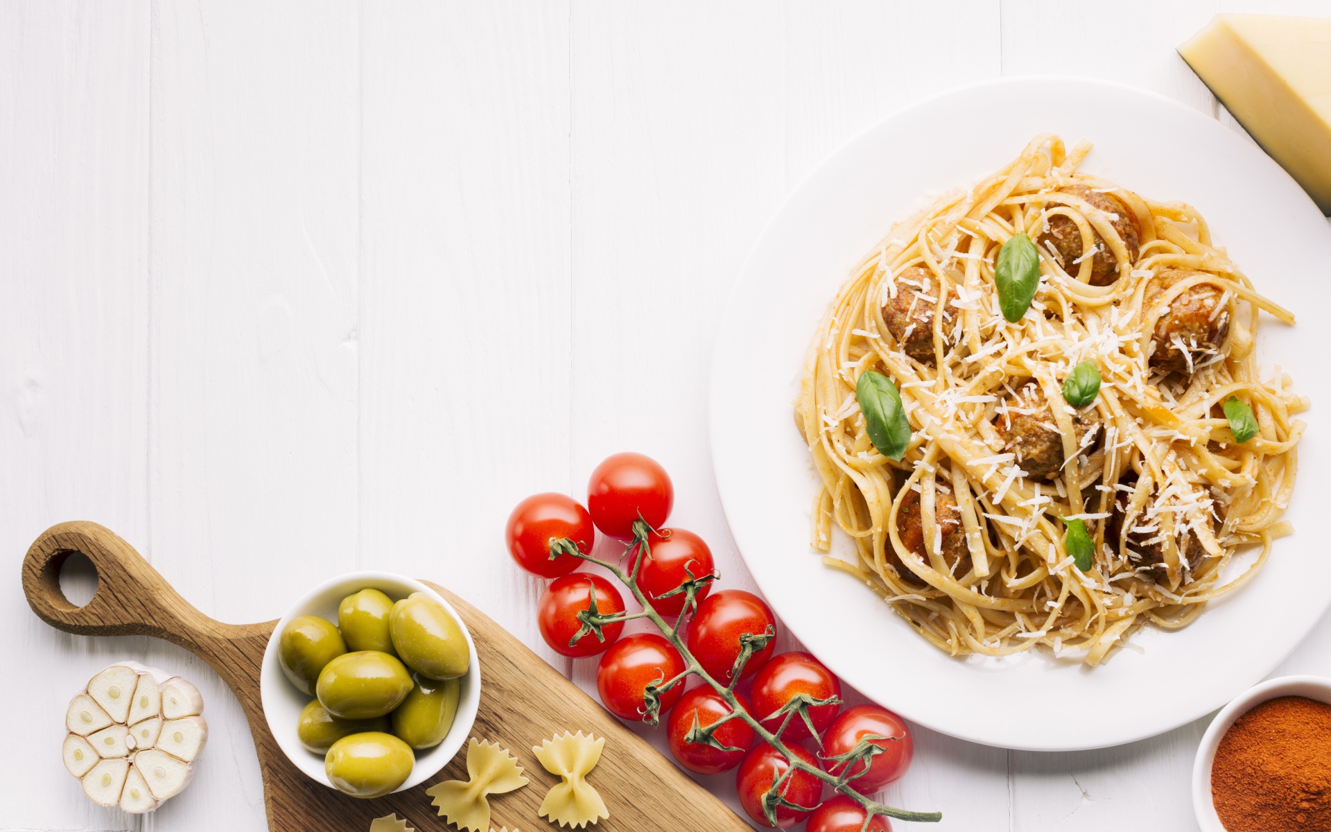 Паста с фрикадельками на столе с помидорами и оливками