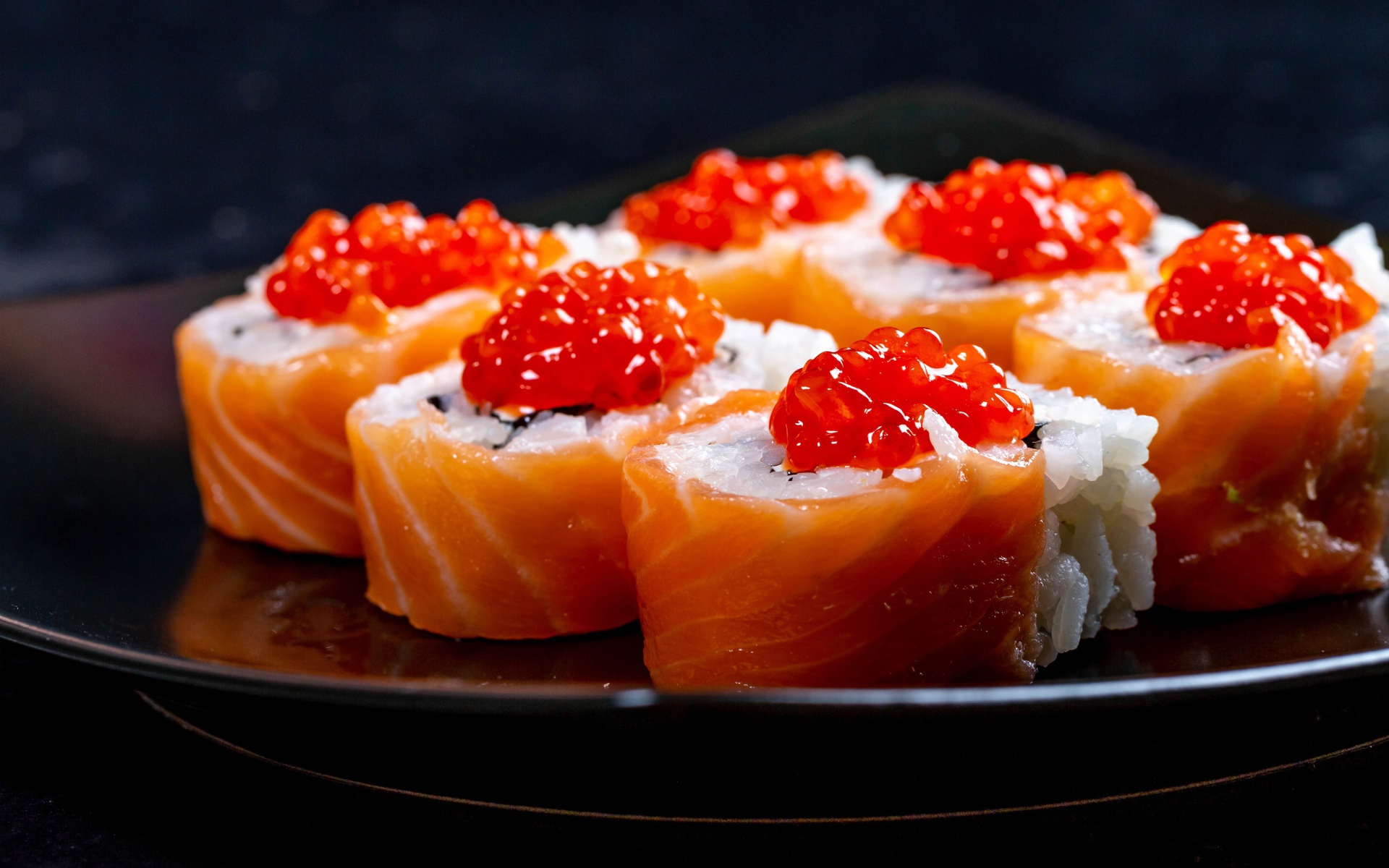 Роллы с красной икрой и рыбой на большой тарелке 