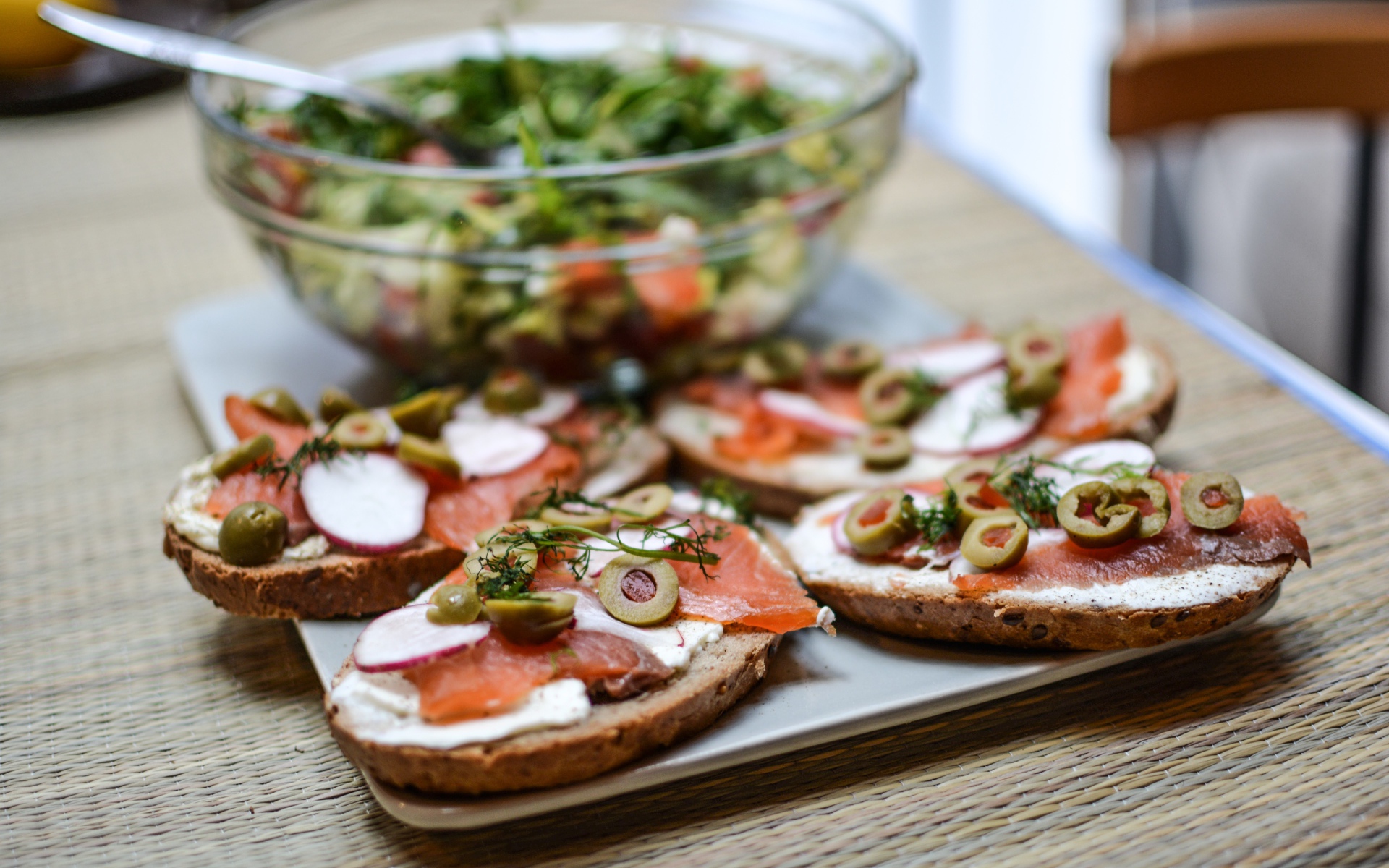 Бутерброды с маслом и красной рыбой на столе с салатом