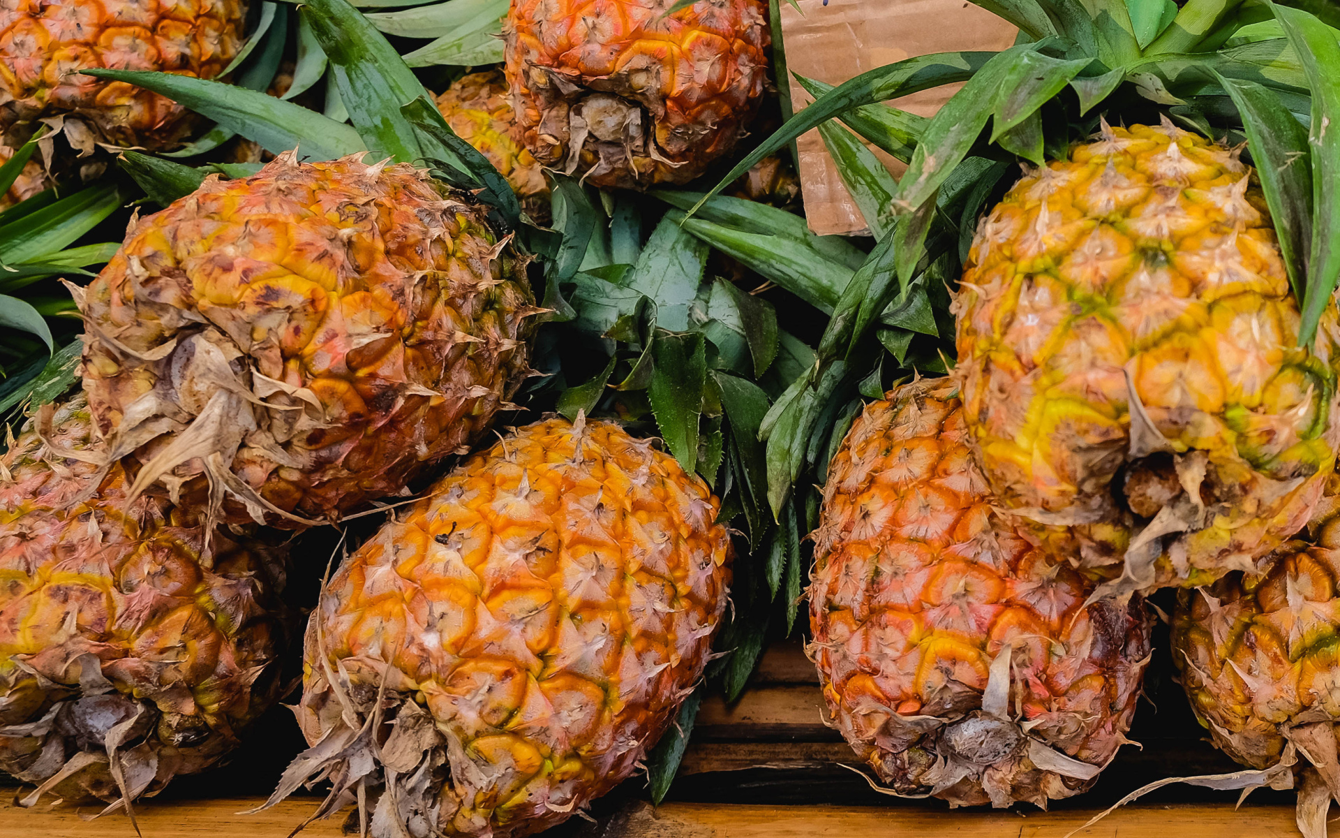 Много больших спелых ананасов на столе 