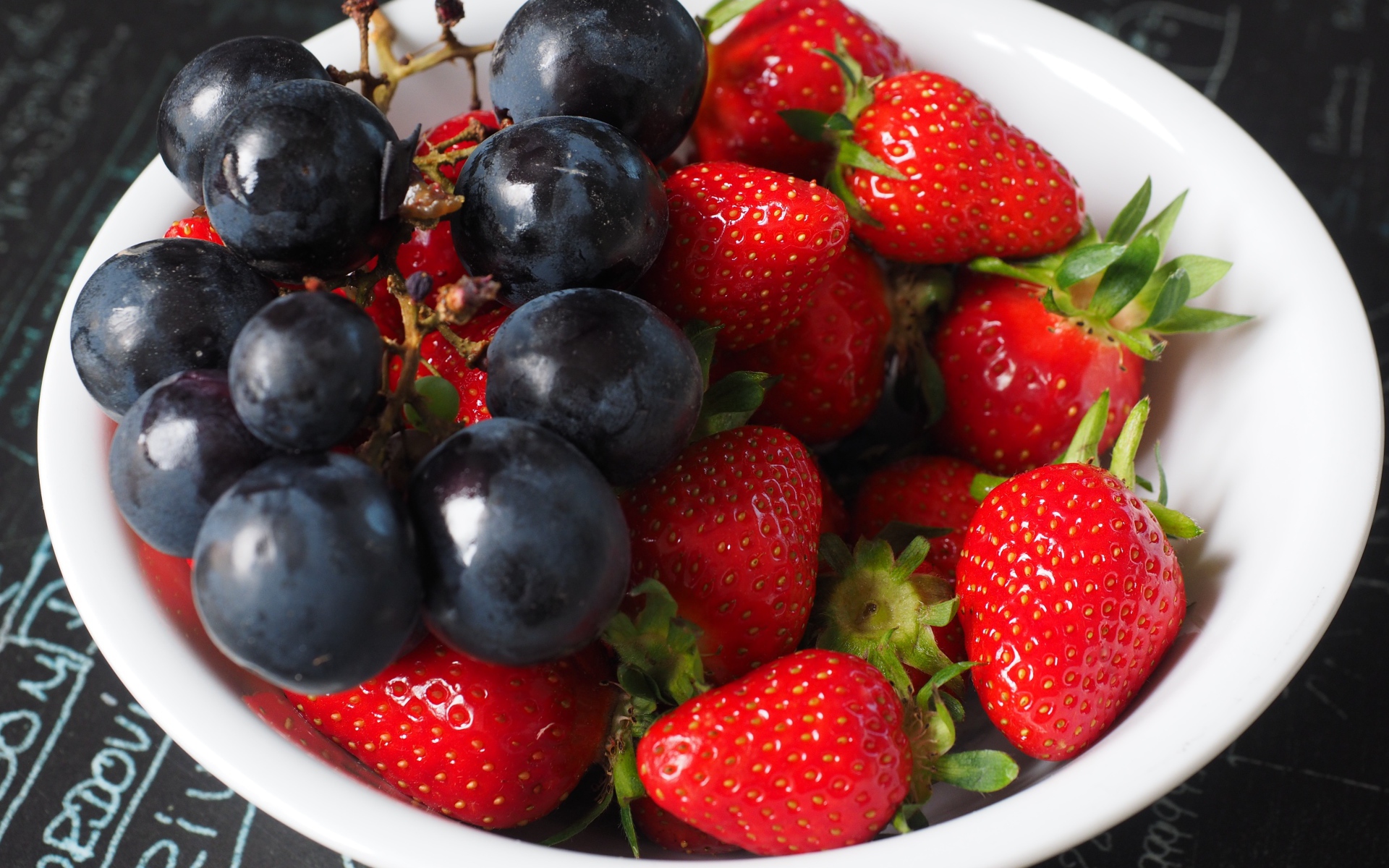 Синий виноград на тарелке с ягодами клубники 