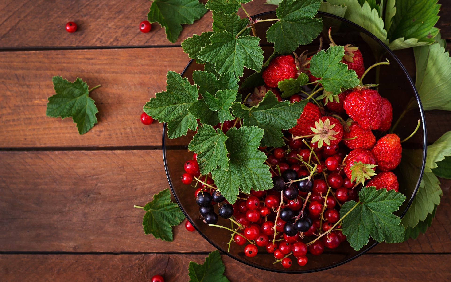 Ягоды смотродины в миске с клубникой и зелеными листьями