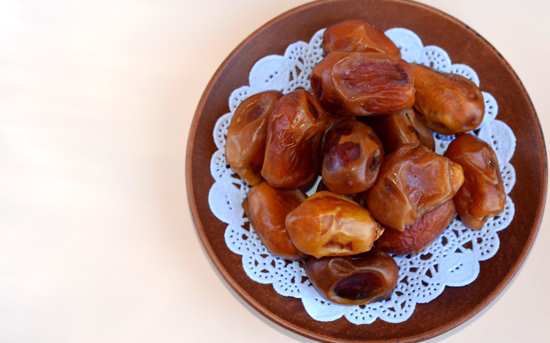Сушеные финики в деревянной миске на белом фоне