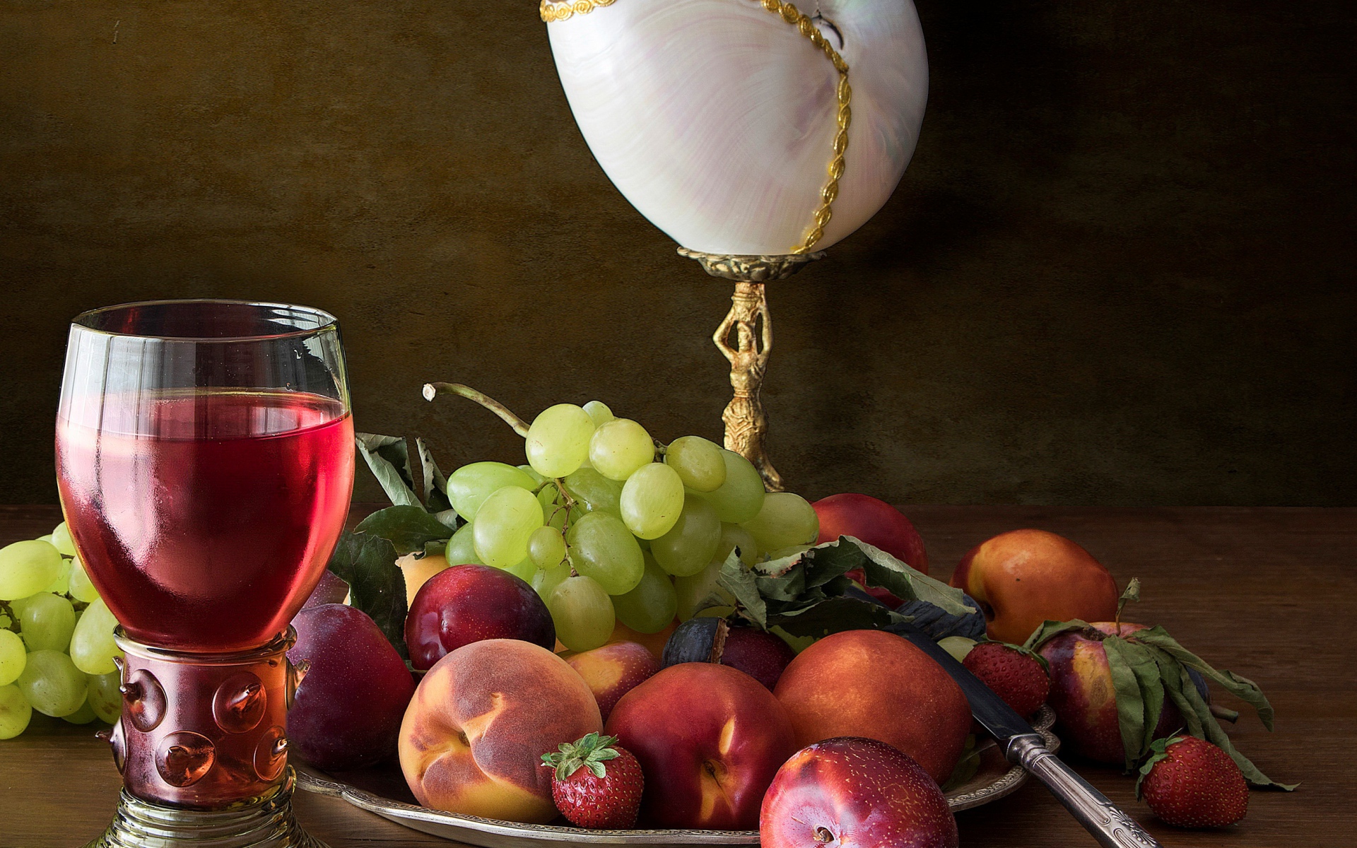 Свежие фрукты и ягоды на столе с вином и лампой 