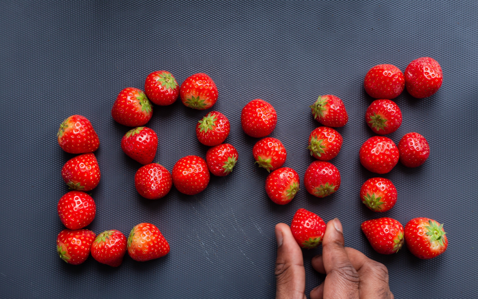 Надпись LOVE выложена из ягод спелой клубники 