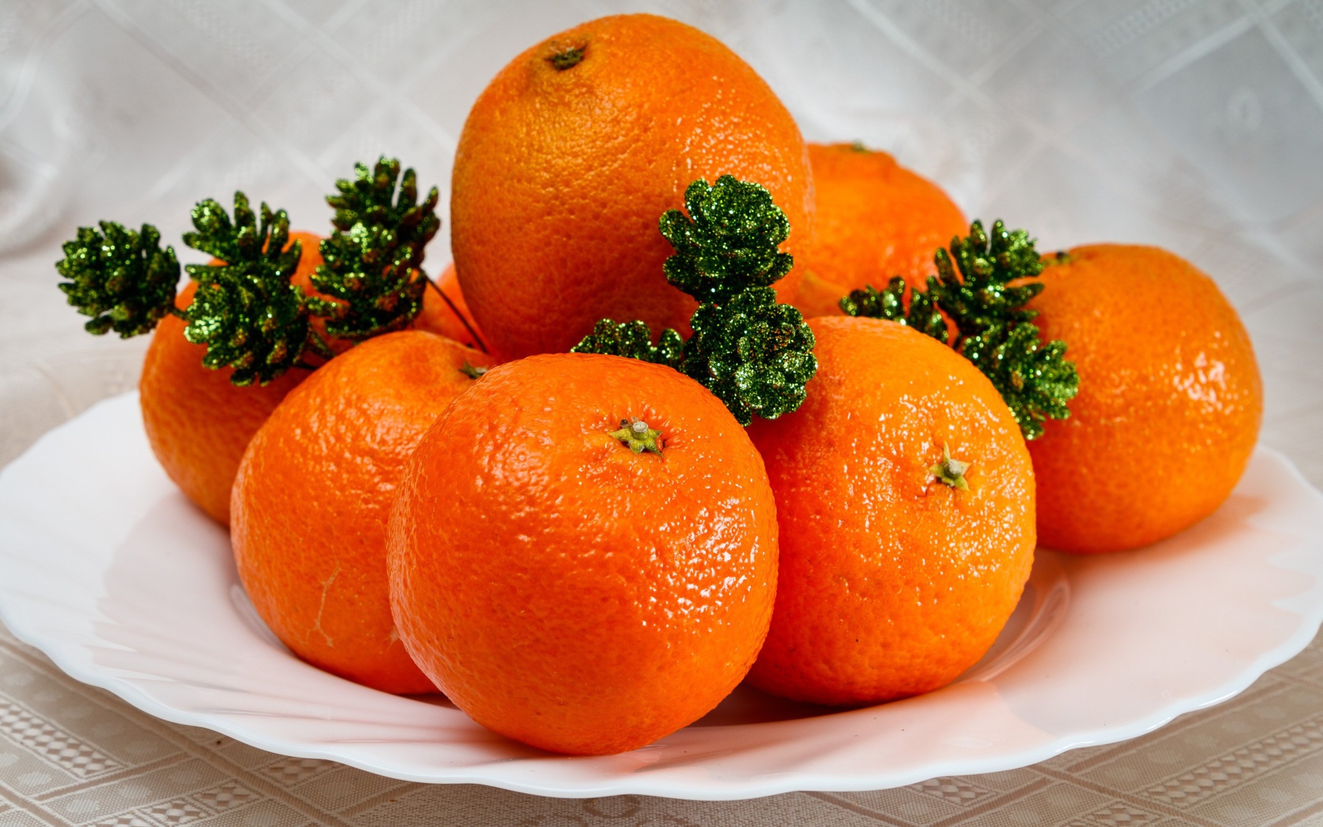 Many orange tangerines on a plate with cones