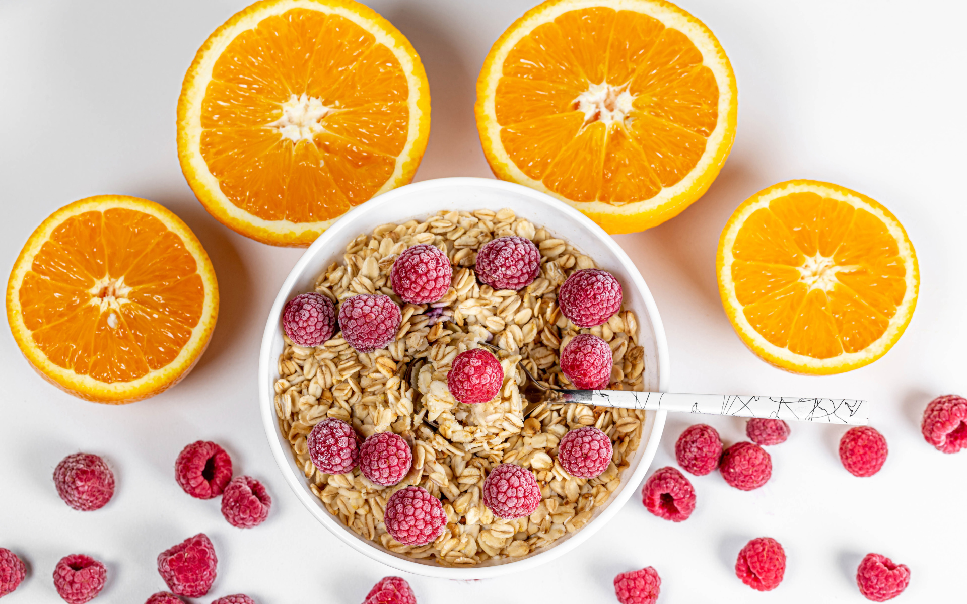 Овсяные хлопья с малиной на белом фоне с апельсинами