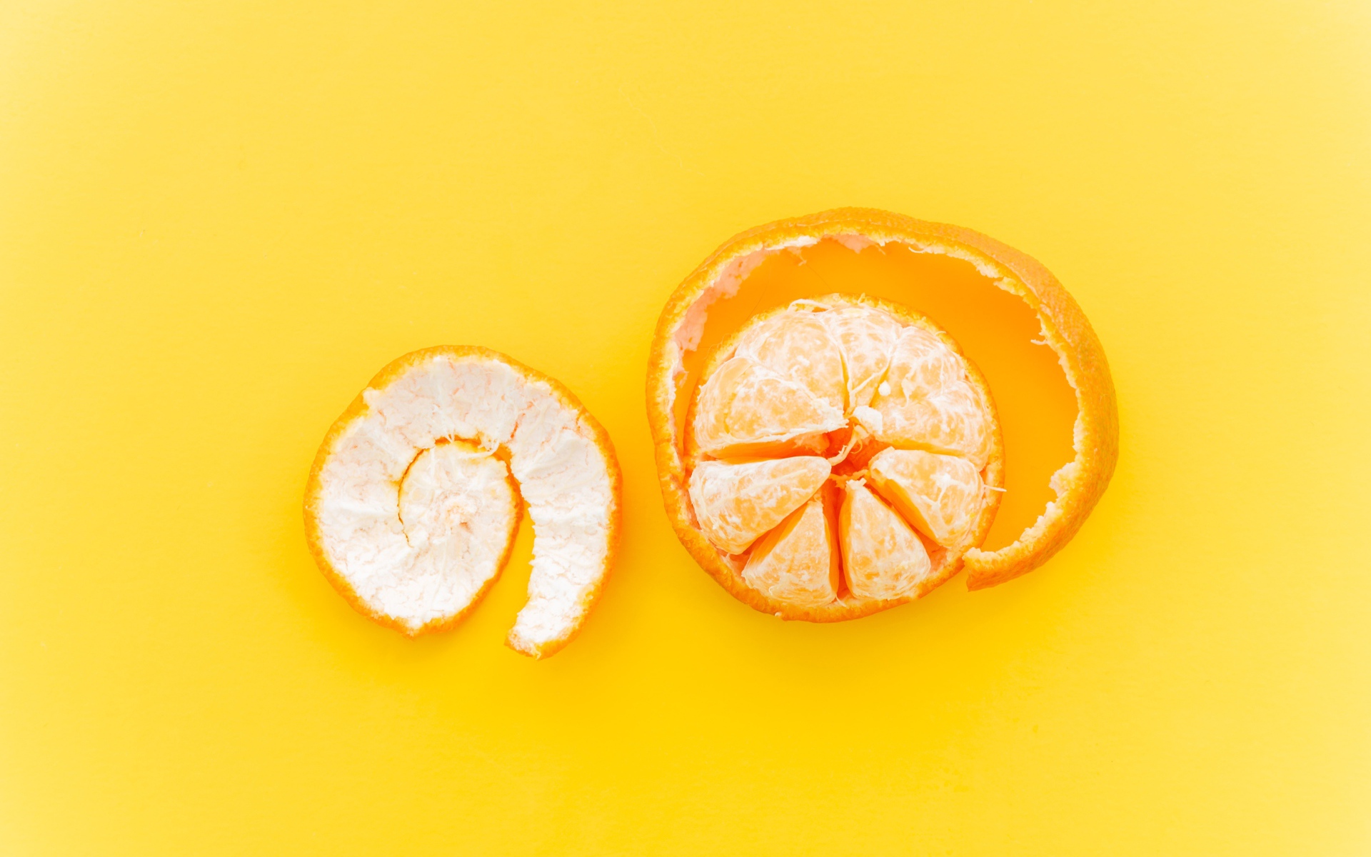 Очищенный мандарин с кожурой на желтом фоне 