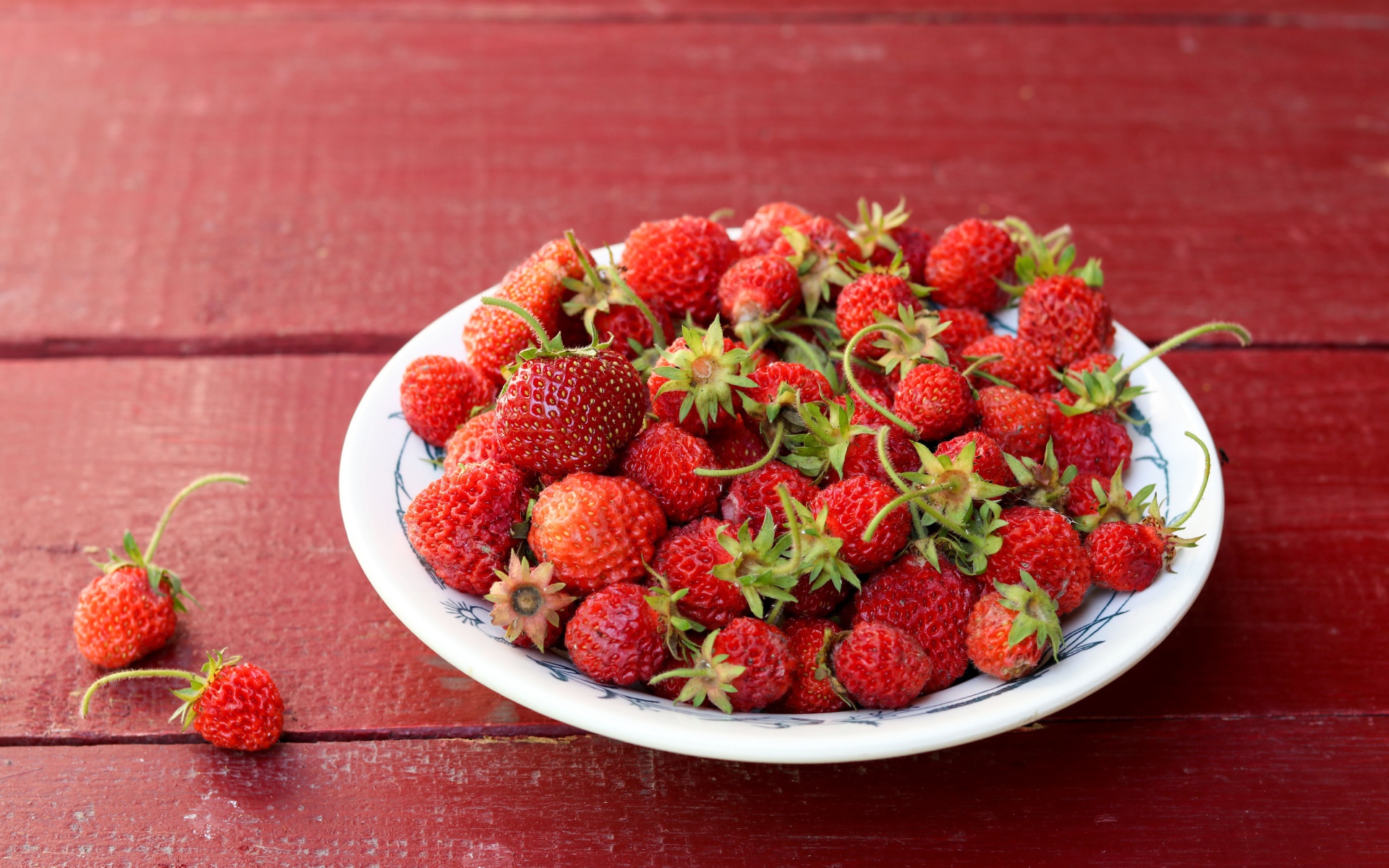 Тарелка со спелой домашней клубникой на столе