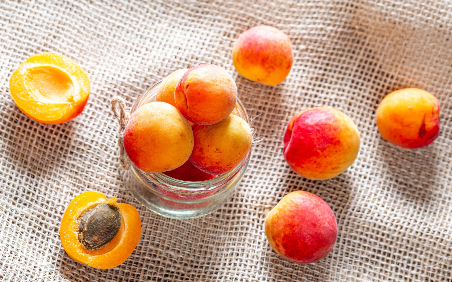 Спелые абрикосы в стеклянной банке на столе 