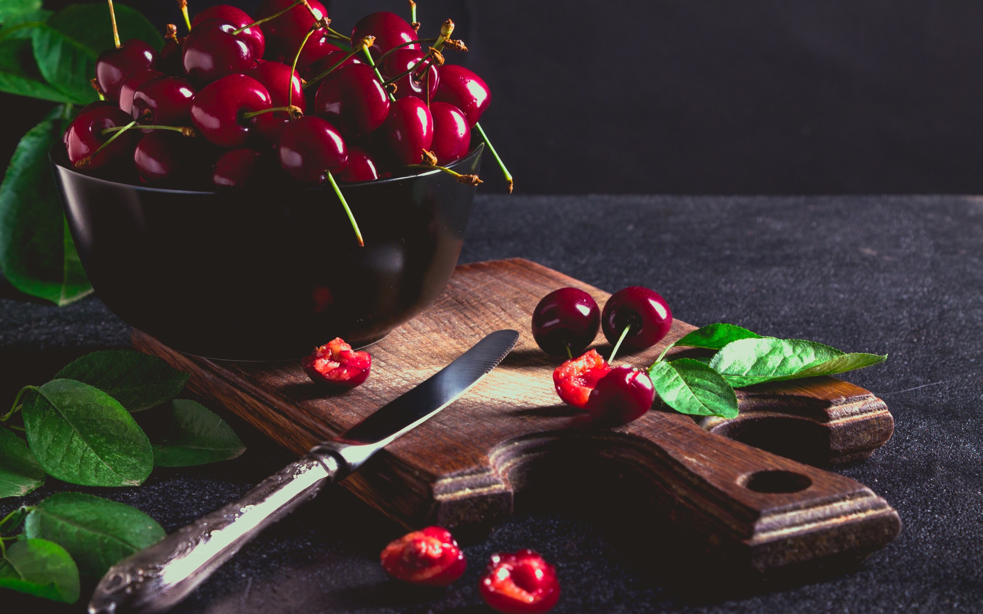 Спелые красные черешни на разделочной доске на столе 