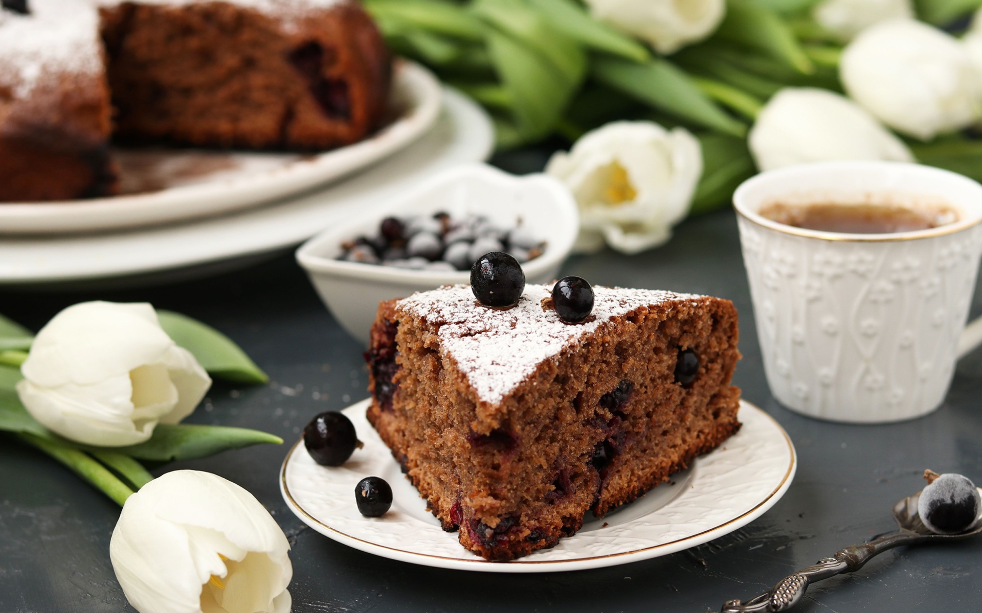 Кусок пирога со смородиной на столе с тюльпанами 
