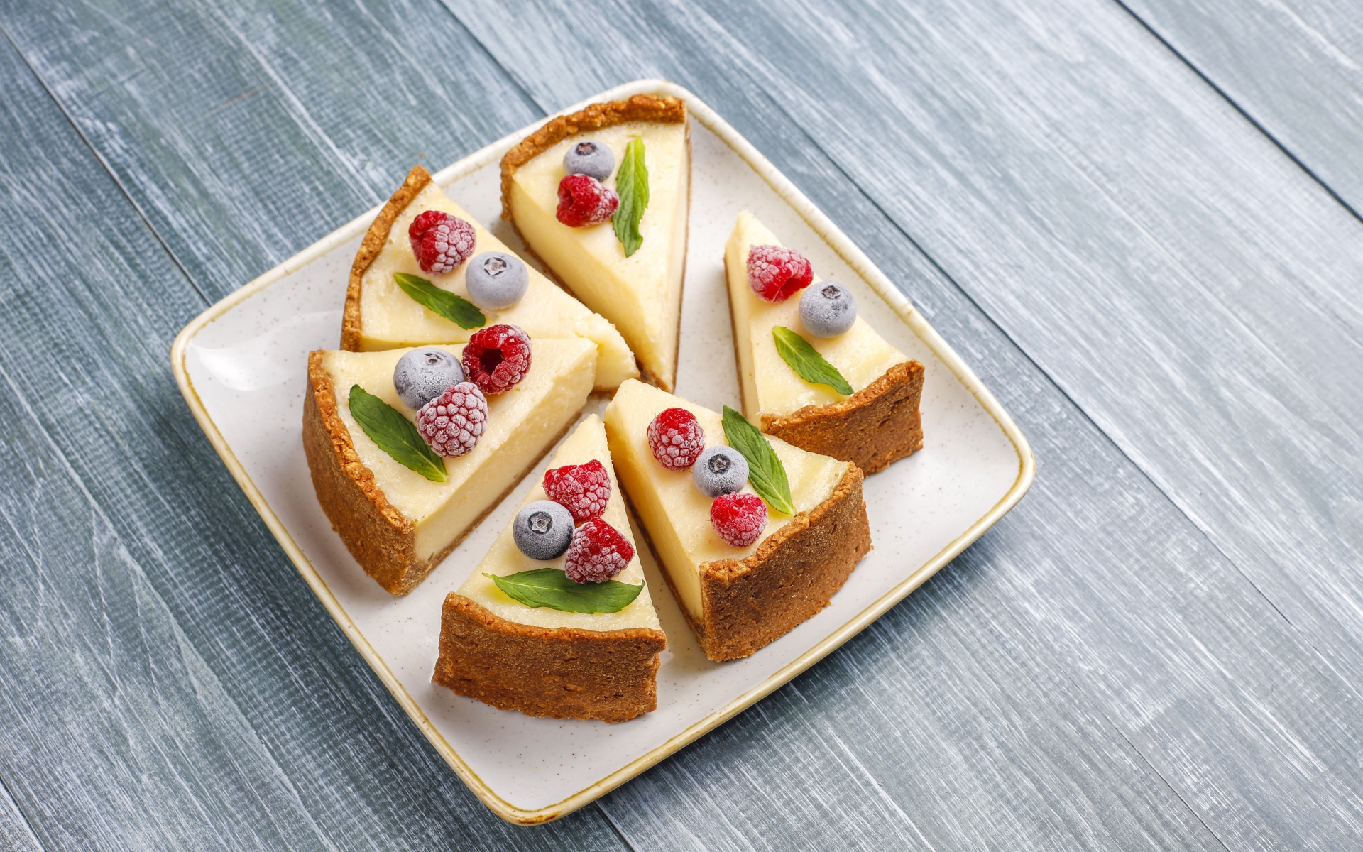 Аппетитный чизкейк с ягодами нарезан кусками на тарелке 