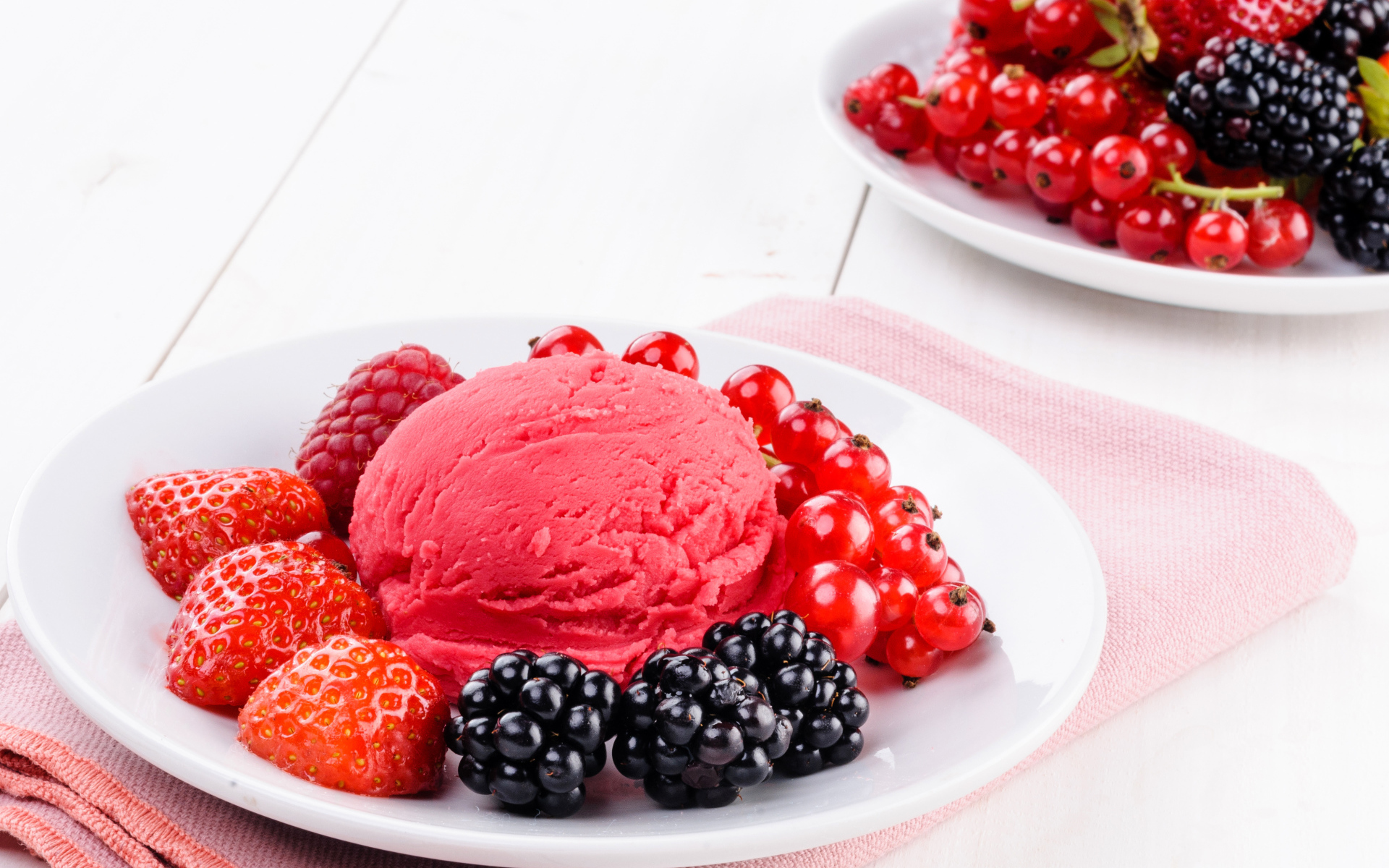 Шарик фруктового мороженого с ягодами на белой тарелке