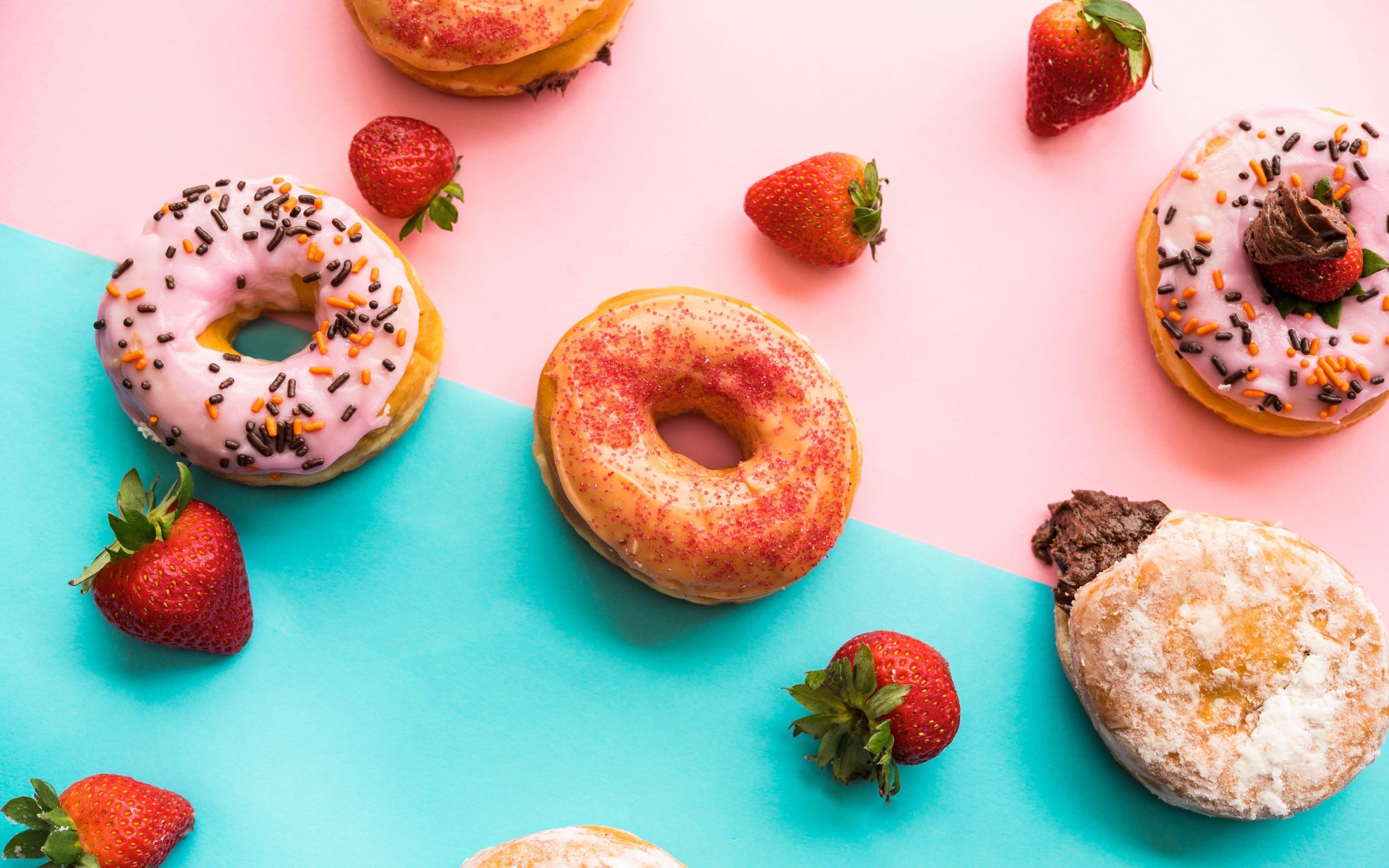 Пончики с глазурью на столе с ягодами клубники