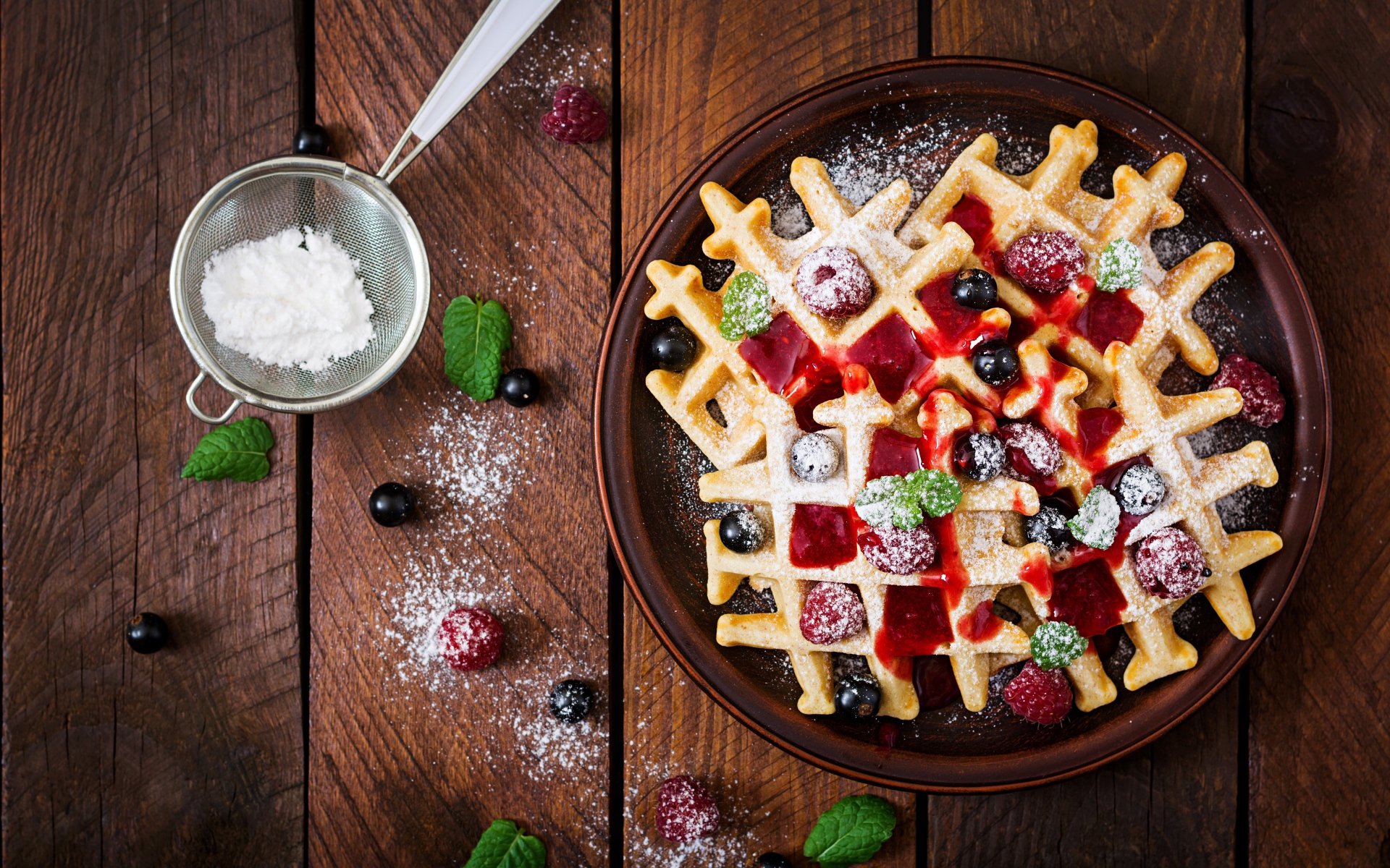 Сладкие медовые вафли на тарелке с ягодами и джемом и сахарной пудрой 