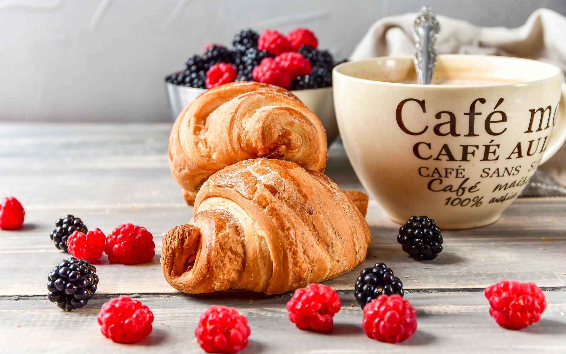 Два круассана на столе с чашкой кофе и ягодами