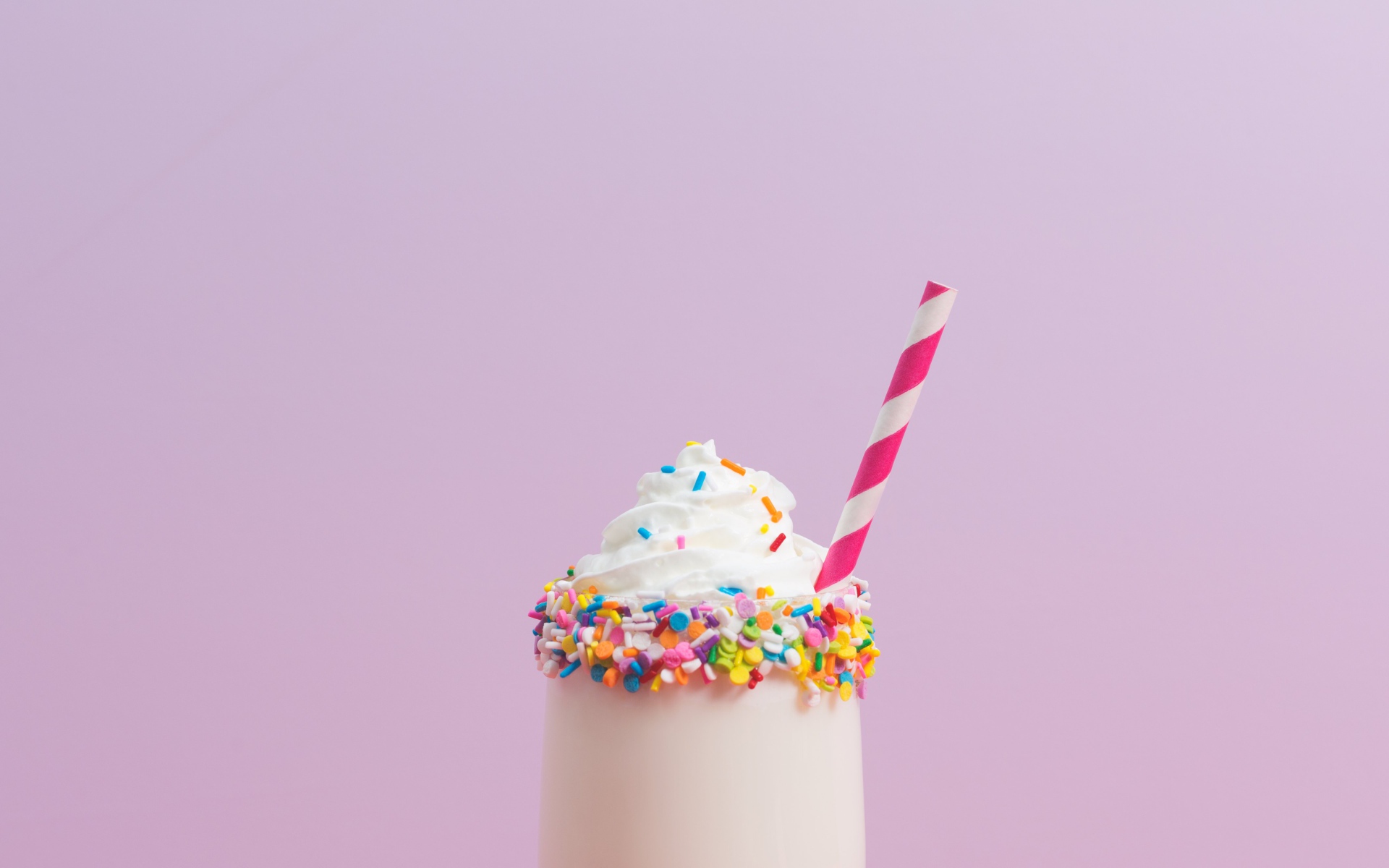 Коктейль  в стакане со взбитыми сливками на розовом фоне