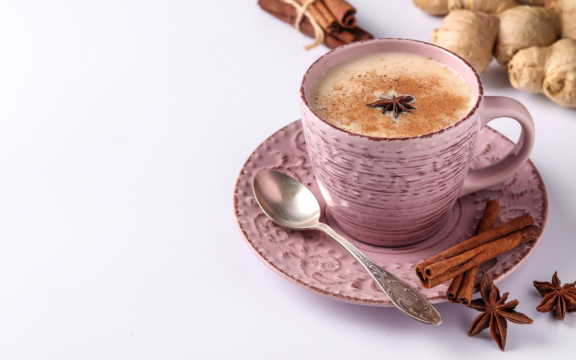 Чашка кофе на столе с корицей, бадьяном и  имбирем на белом фоне 