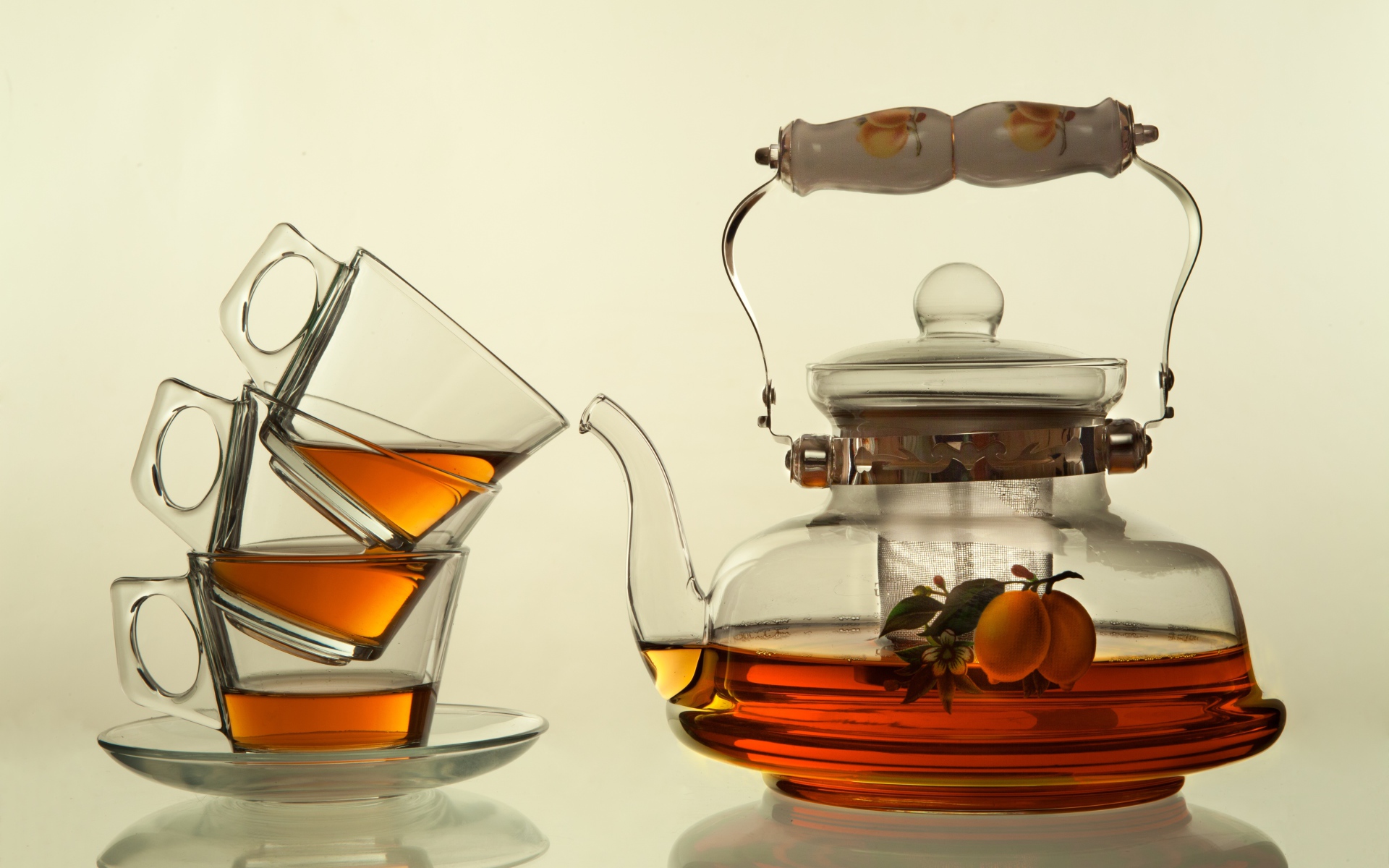 Стеклянный чайник с чашками на белом фоне